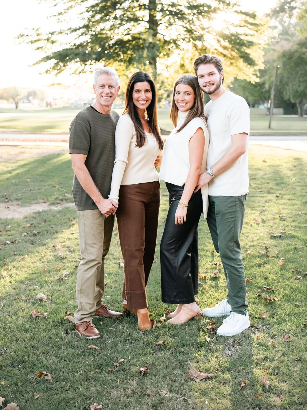 Group photo showing legs and feet of four people standing together on grass in casual attire.