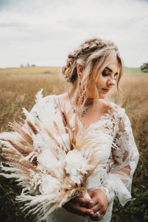 Bride holding beautiful dried flower bouquet in white and neutral tones.