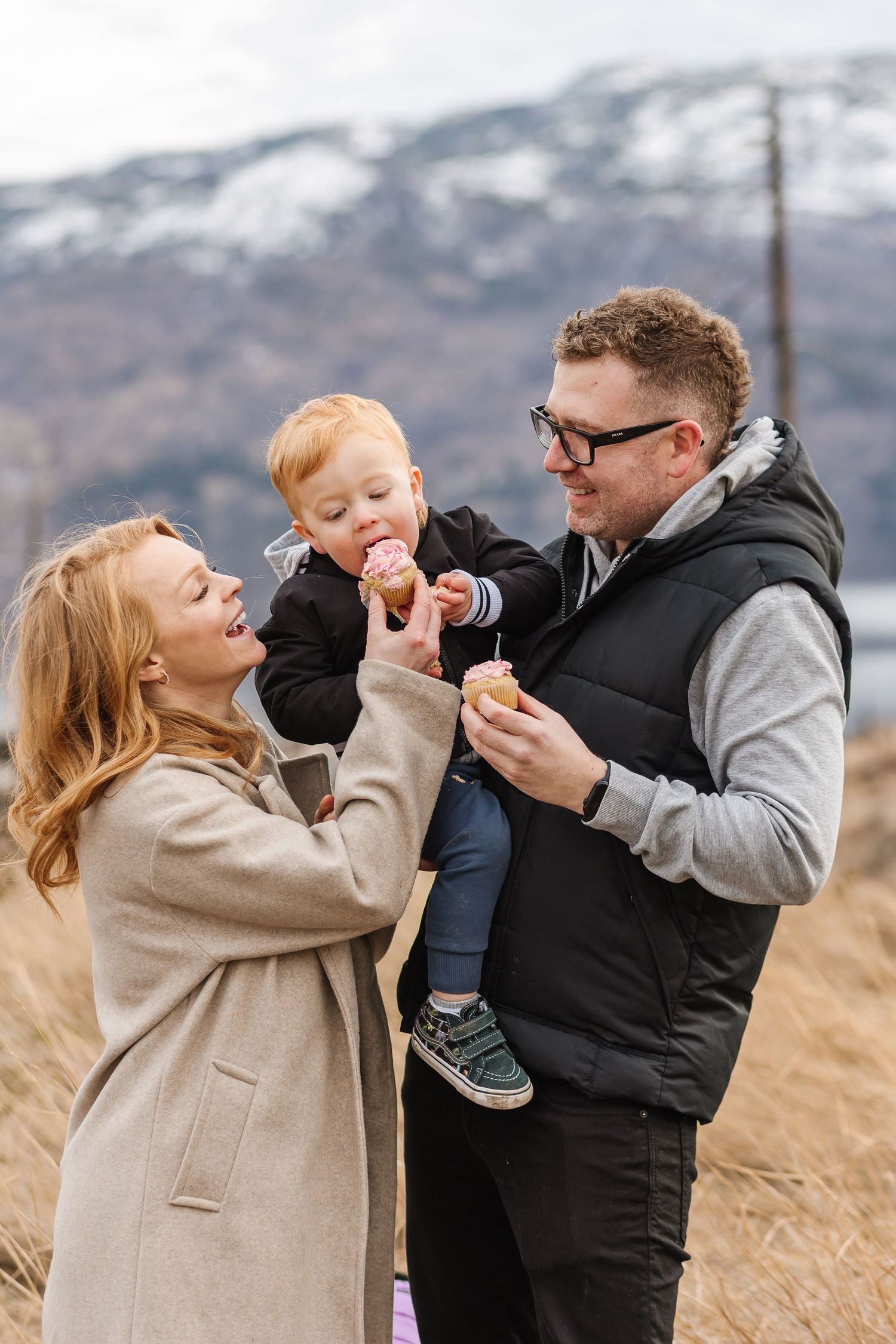 Family shares a playful moment outdoors with snowy mountains in the background for a family photoshoot in West Kelowna