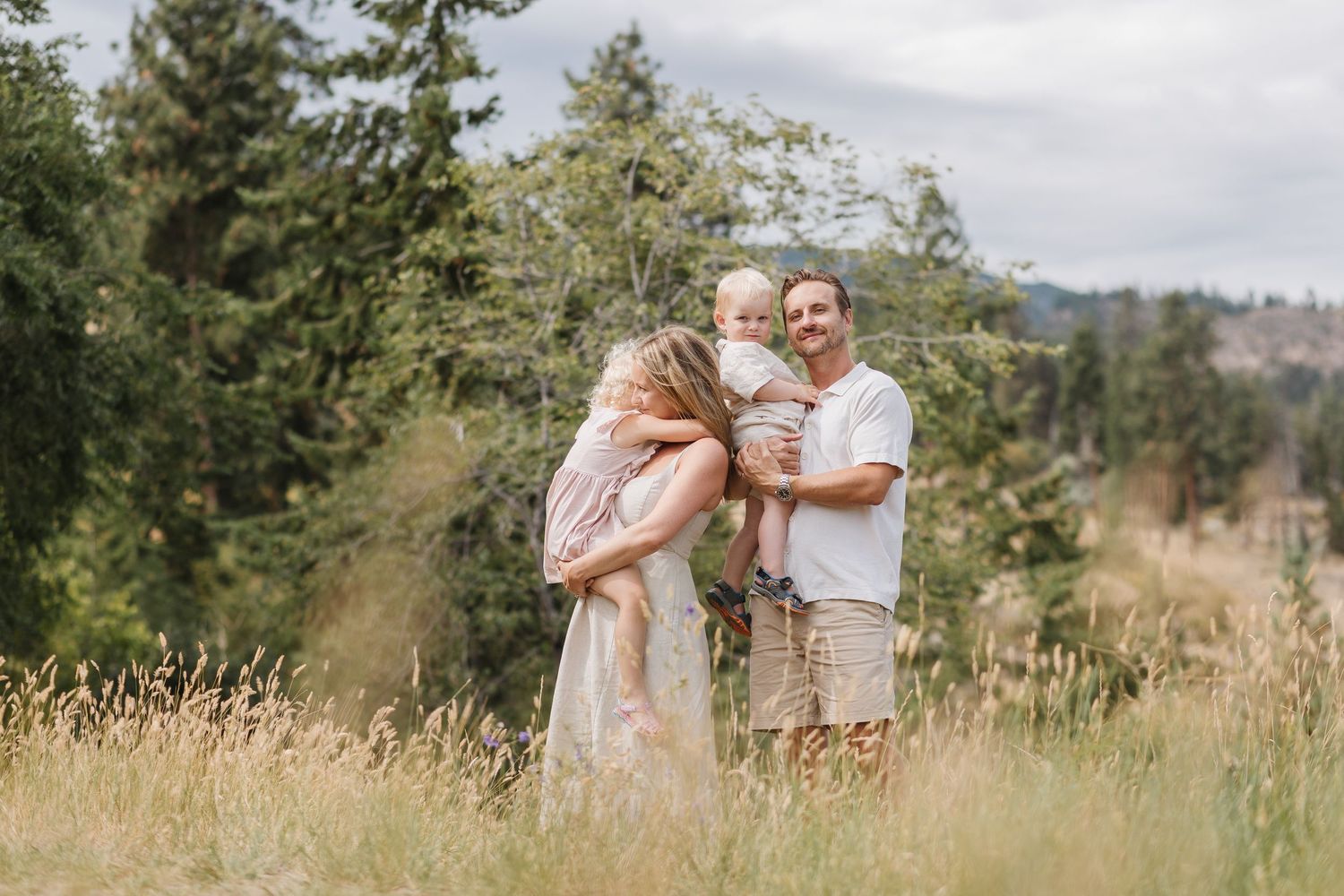 A collection of candid family portraits in a natural setting with mountains and tall grass in the background.