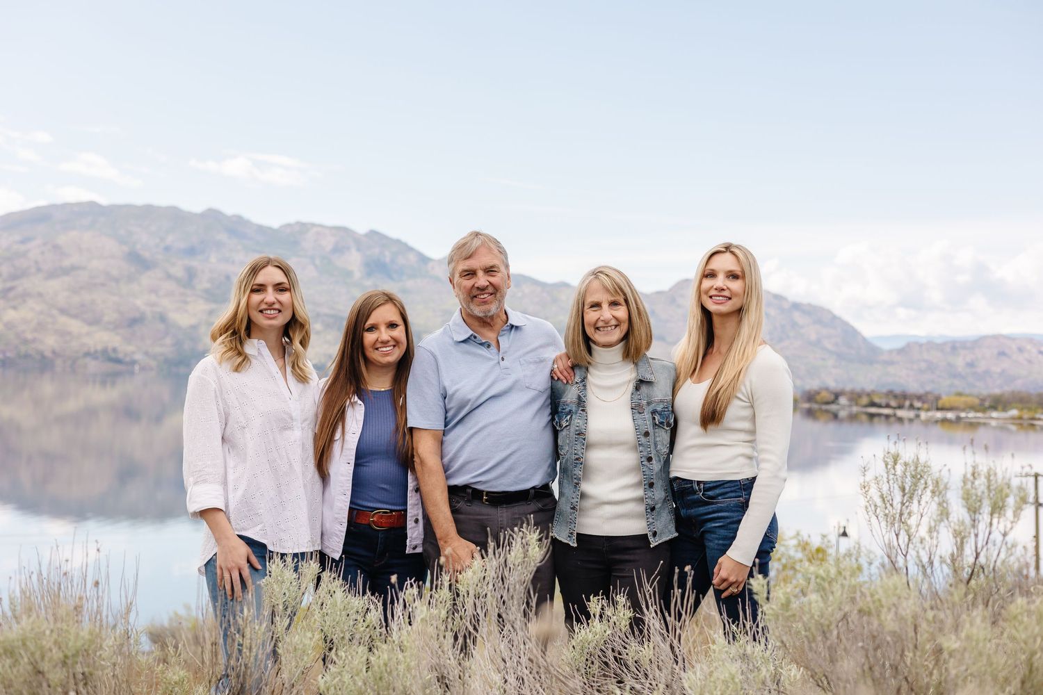 Family group photo with mountain lake backdrop on a clear day in west kelowna at sanctuary gardens