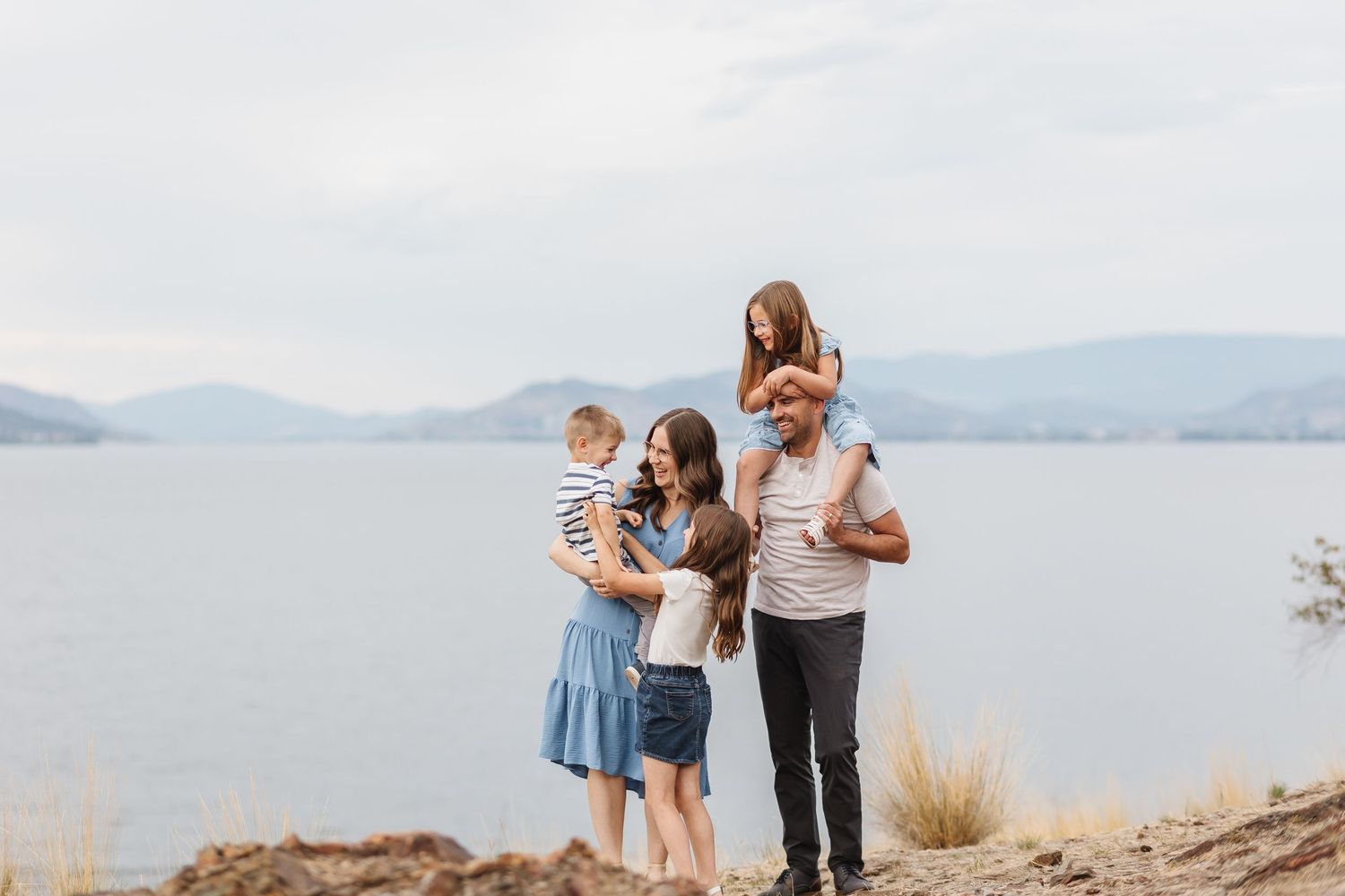 Family enjoying scenic views together at a mountain lake overlook on a bright sunny day.