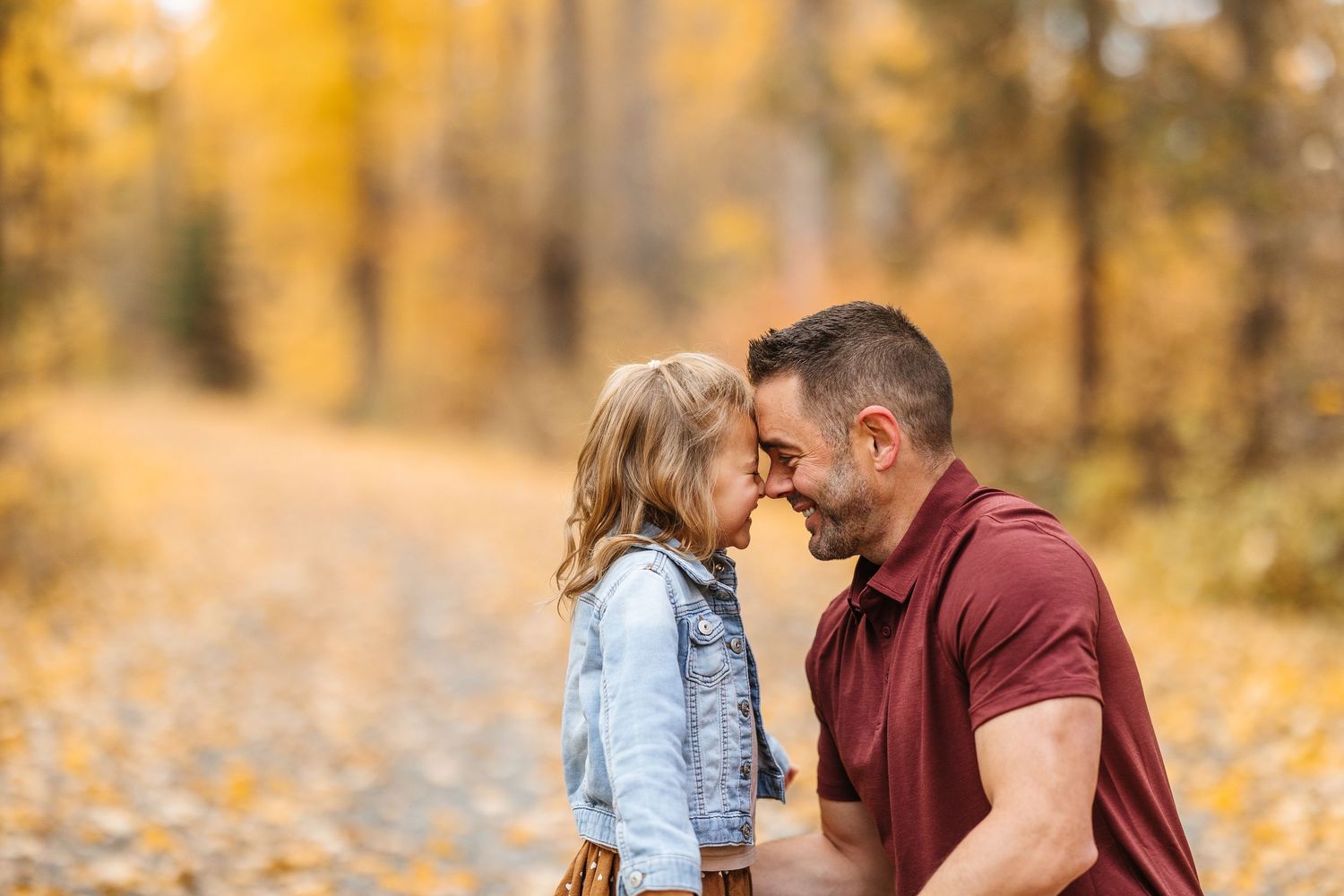 Romantic couple walking together through a golden autumn forest with fallen leaves on the ground.