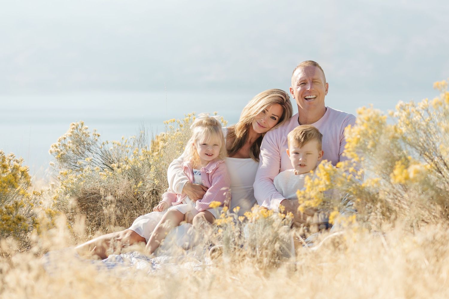 Family enjoying a sunset photoshoot in a golden field with autumn colors and warm lighting.