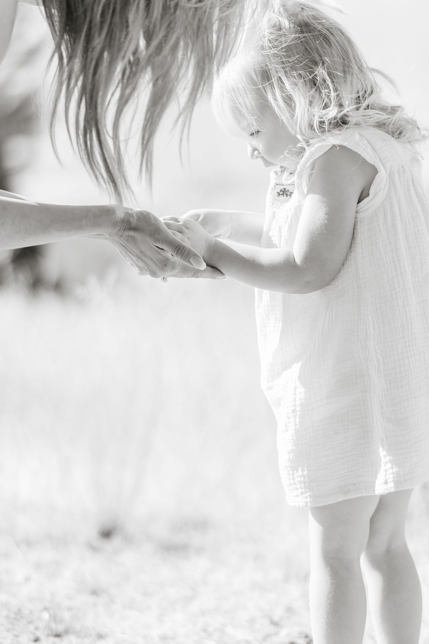 A soft black and white photograph shows a small child in a white dress standing in dreamy sunlight.