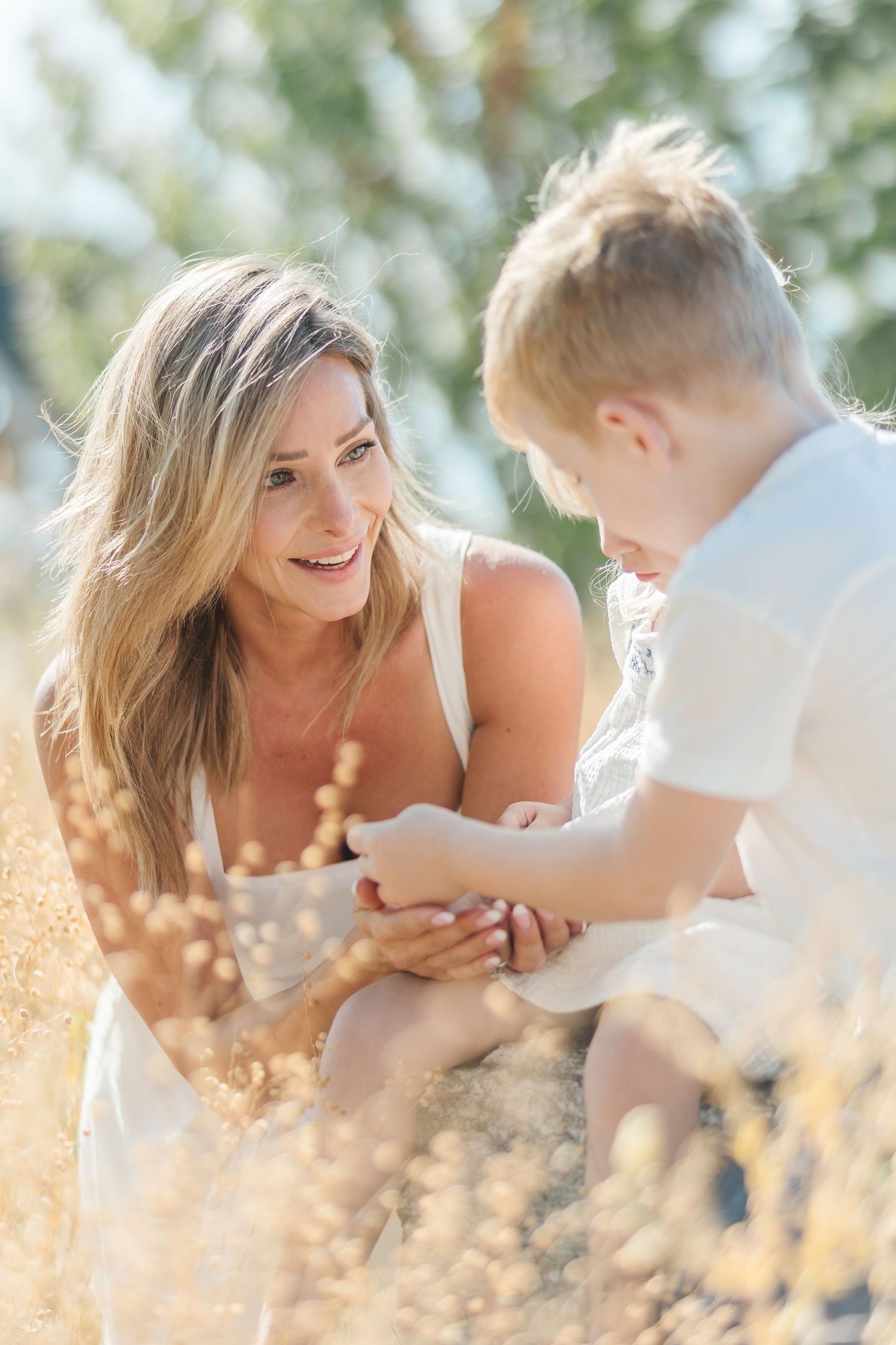 Romantic couple sharing tender moments while lying in sunlit grass during a summer photoshoot.