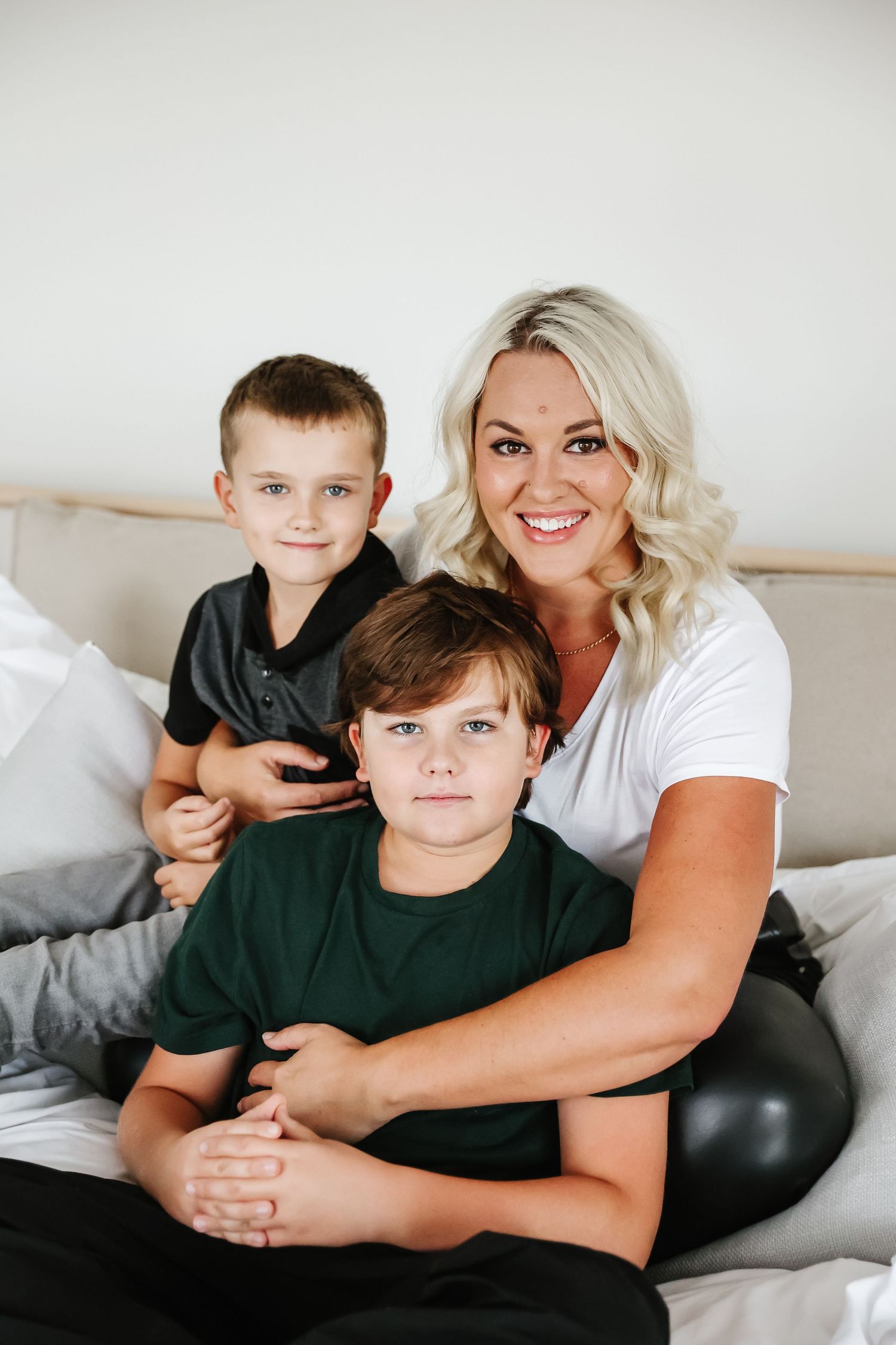 A casual indoor portrait on a comfortable bed with neutral decor and white walls in west Kelowna in natural light