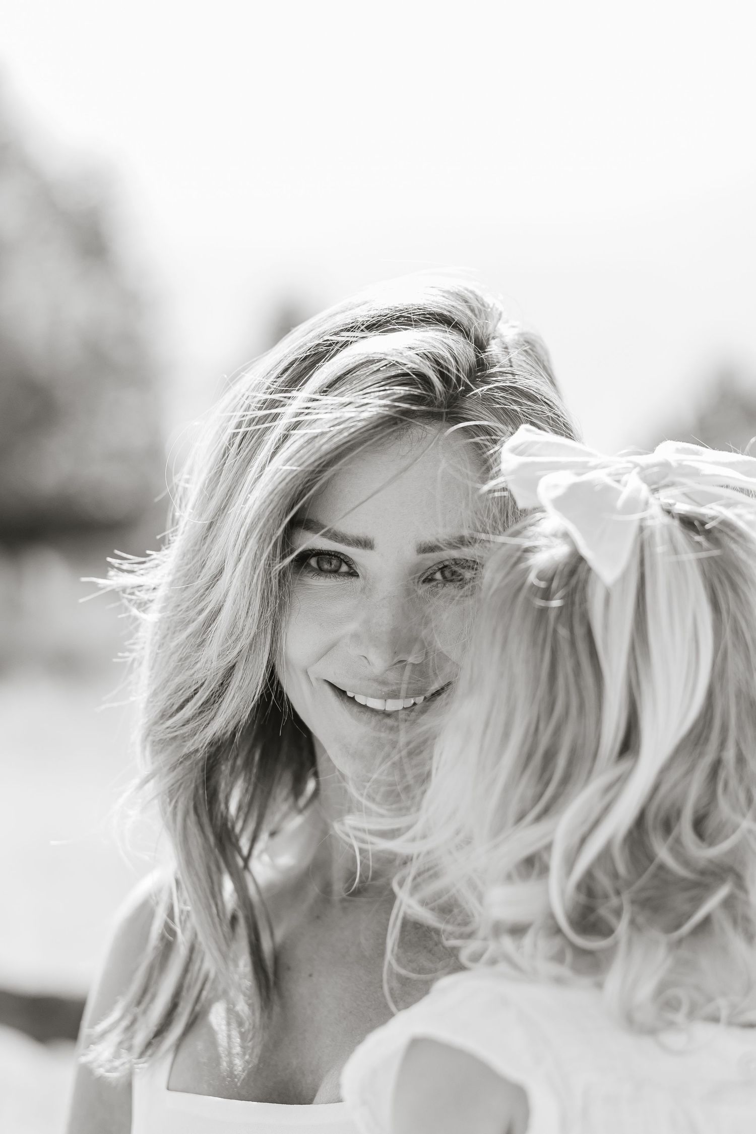 Close-up black and white portraits showing joyful expressions in natural outdoor lighting.