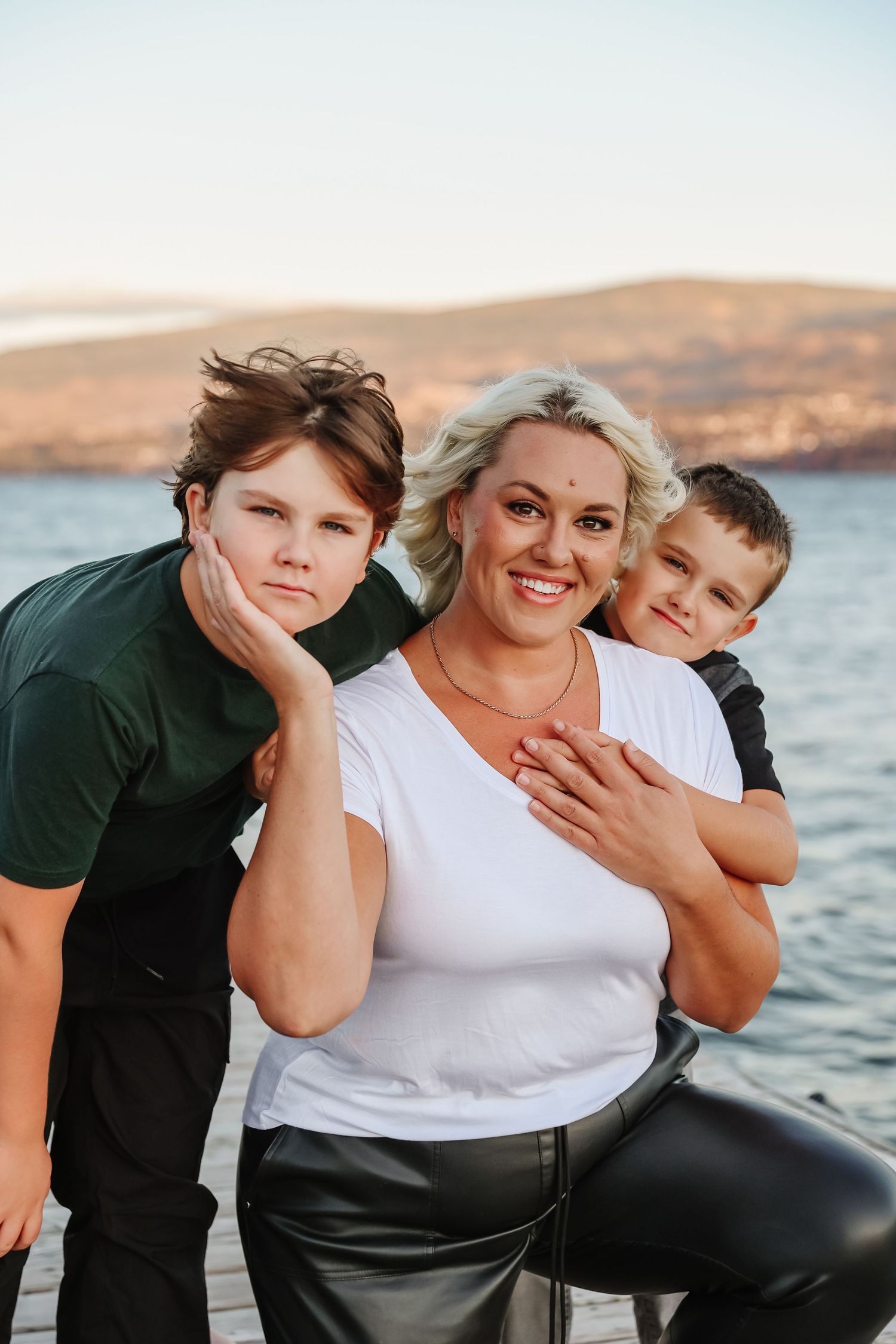 A waterfront family portrait for family photos with mountains and sunset colors in the background In west kelowna