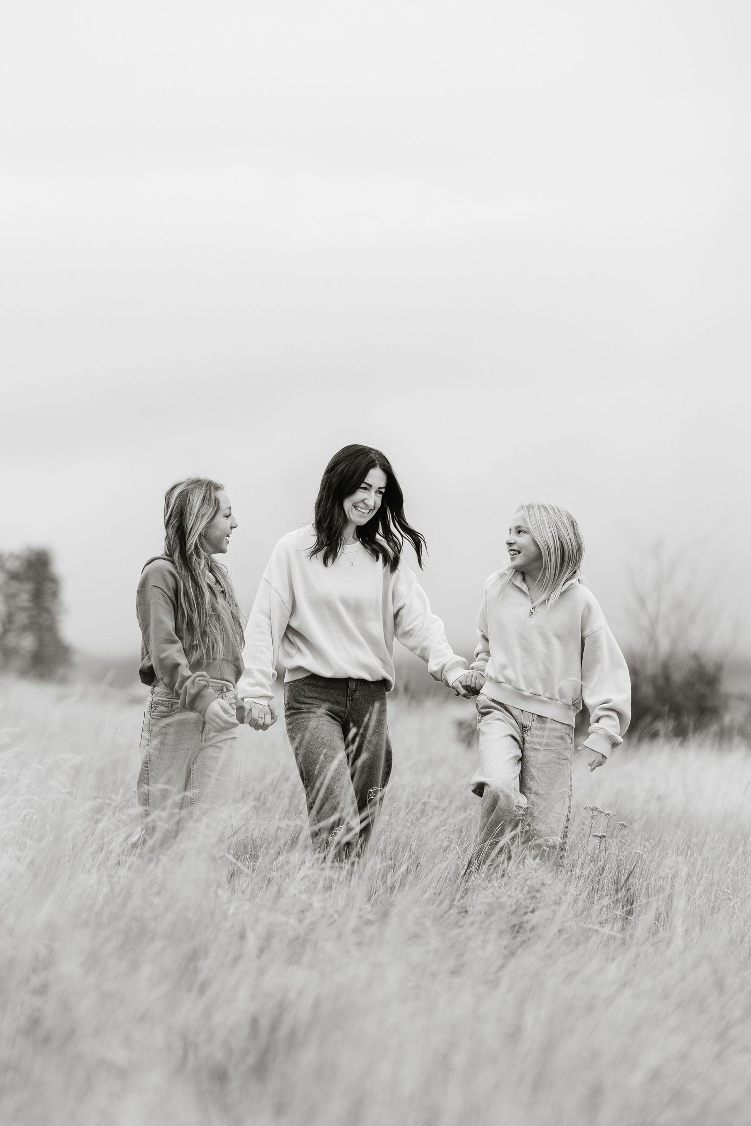 A group of friends walking through a serene field of tall grass in black and white.