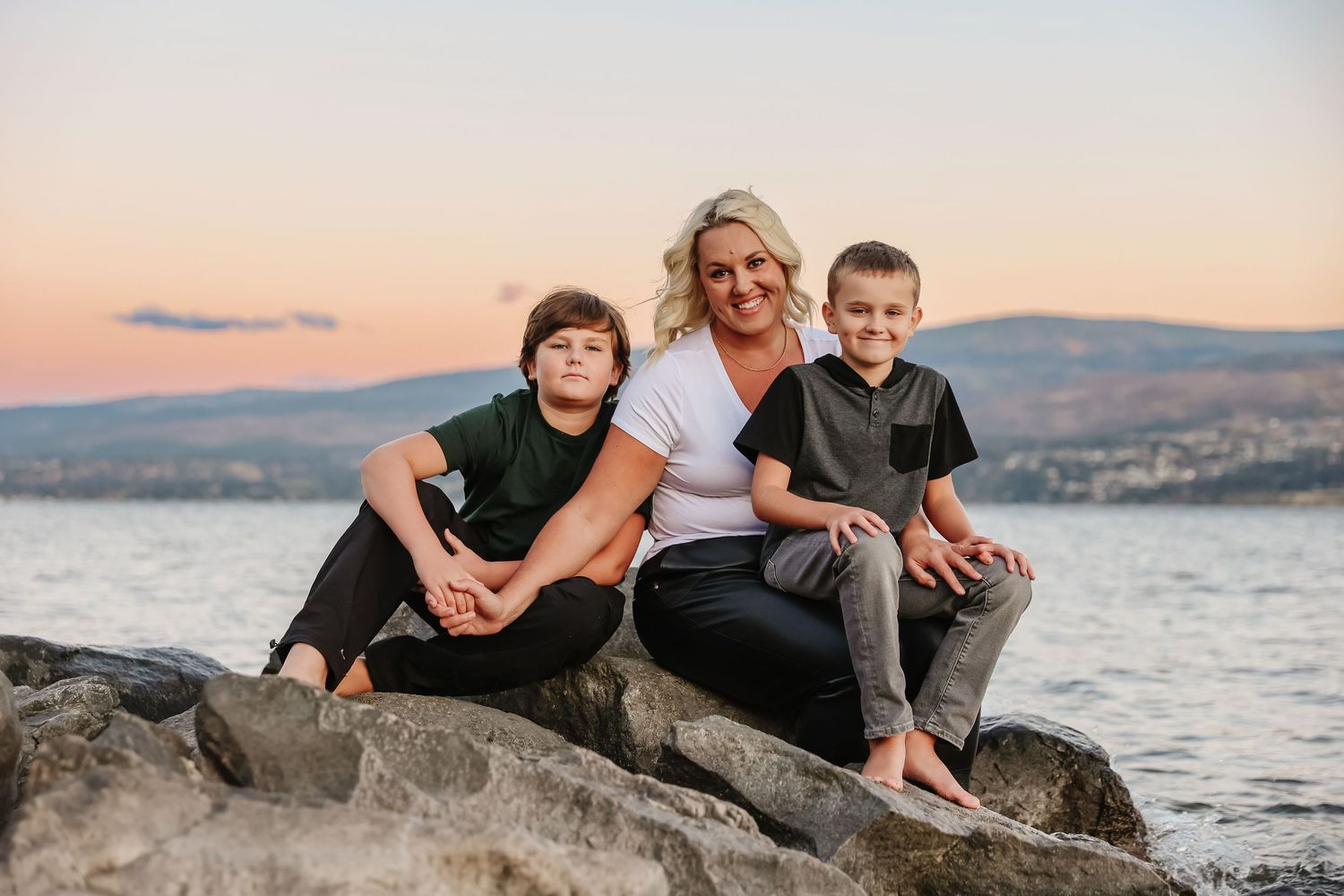 A sunset family portrait photoshoot on rocks with mountains and okanagan lake in the background in West Kelowna British columbia