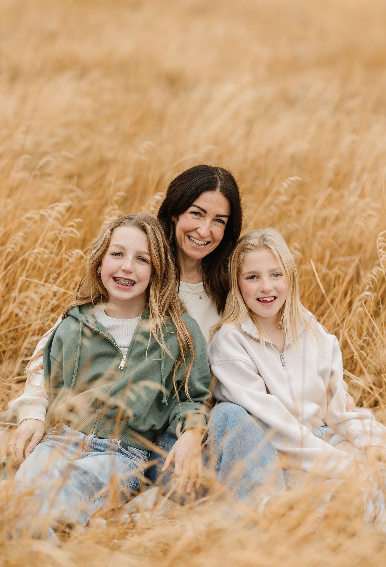 Children sitting together and laughing in a golden wheat field on a sunny day.
