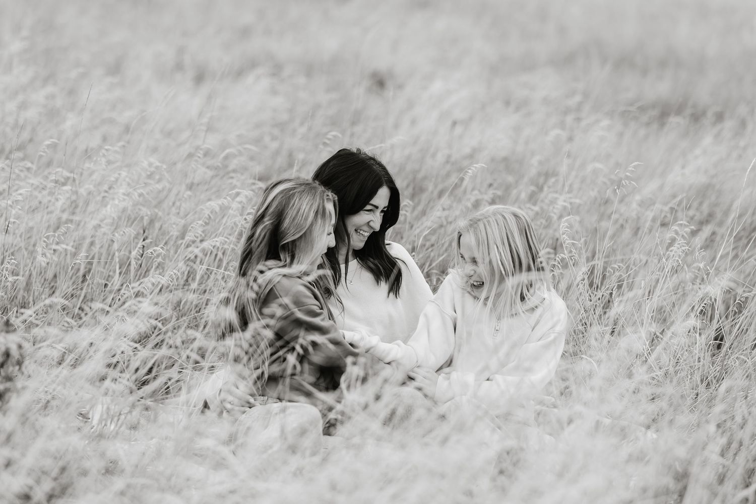 A series of black and white photographs showing people lying in tall grass or meadow fields.