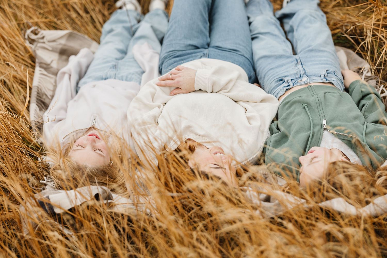 People lying together in golden wheat field on a sunny day creating a dreamy outdoor portrait scene.