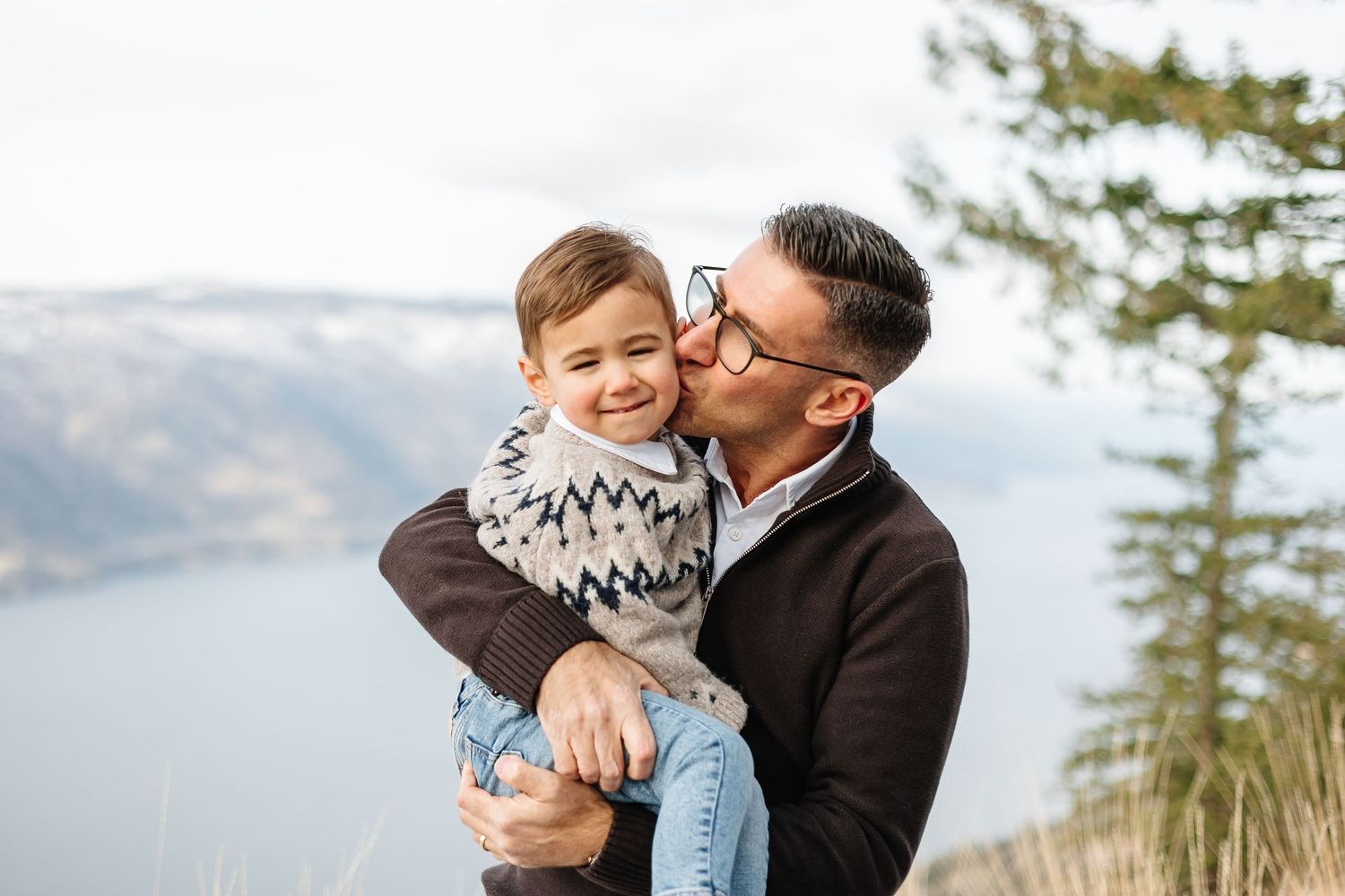 Heartwarming winter portrait session with snowy mountains and evergreen trees in the background in kelowna