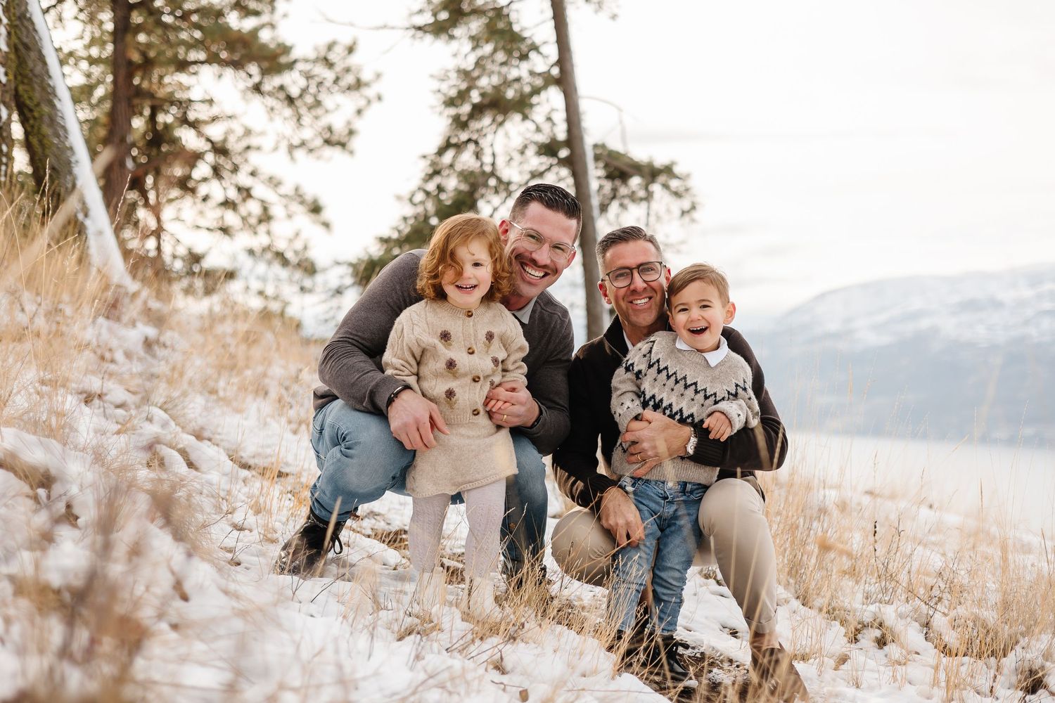 Family enjoying playful moments together on a snowy mountain overlook for family photos in kelowna
