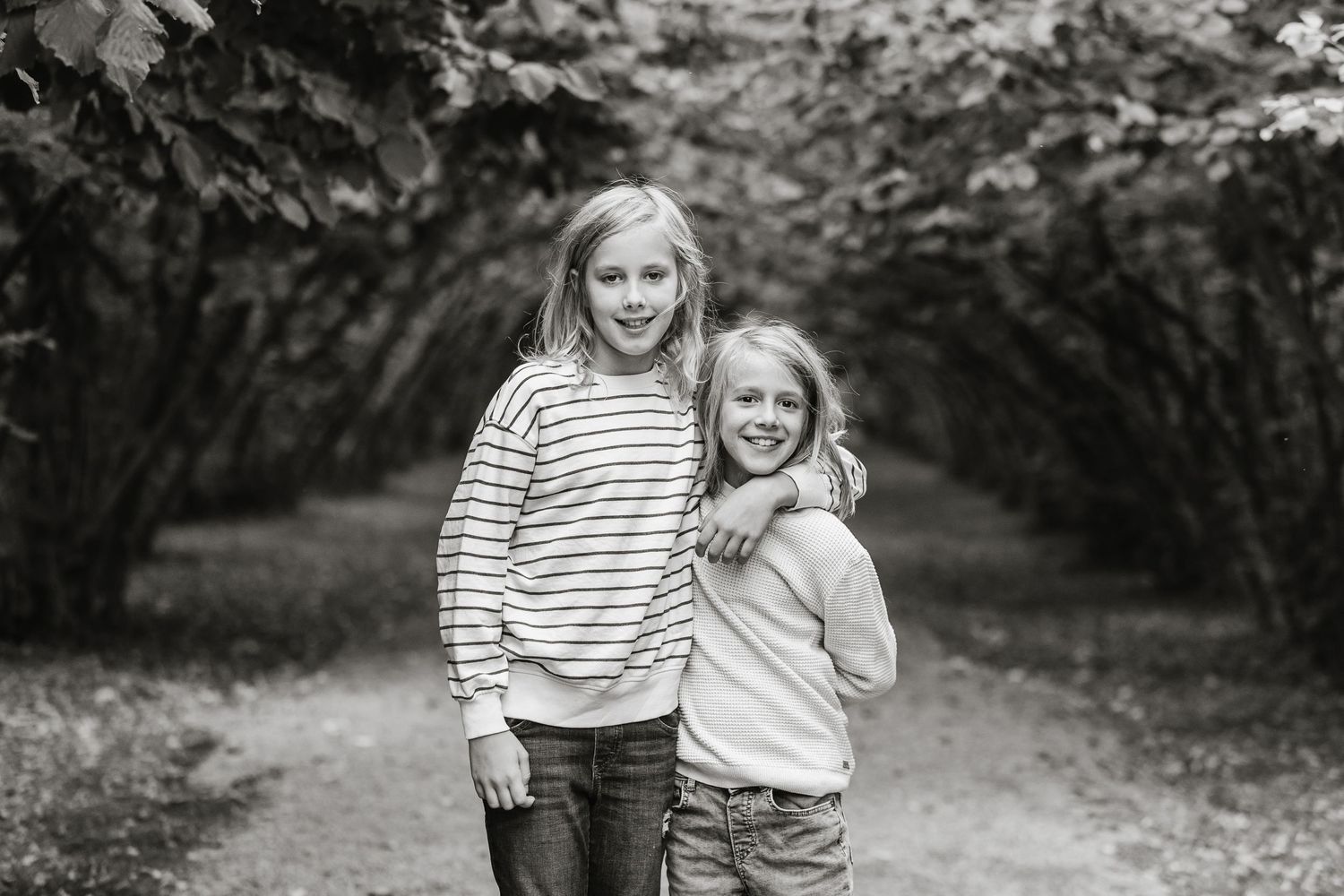 A series of black and white photos showing joyful moments between two people in a garden setting.