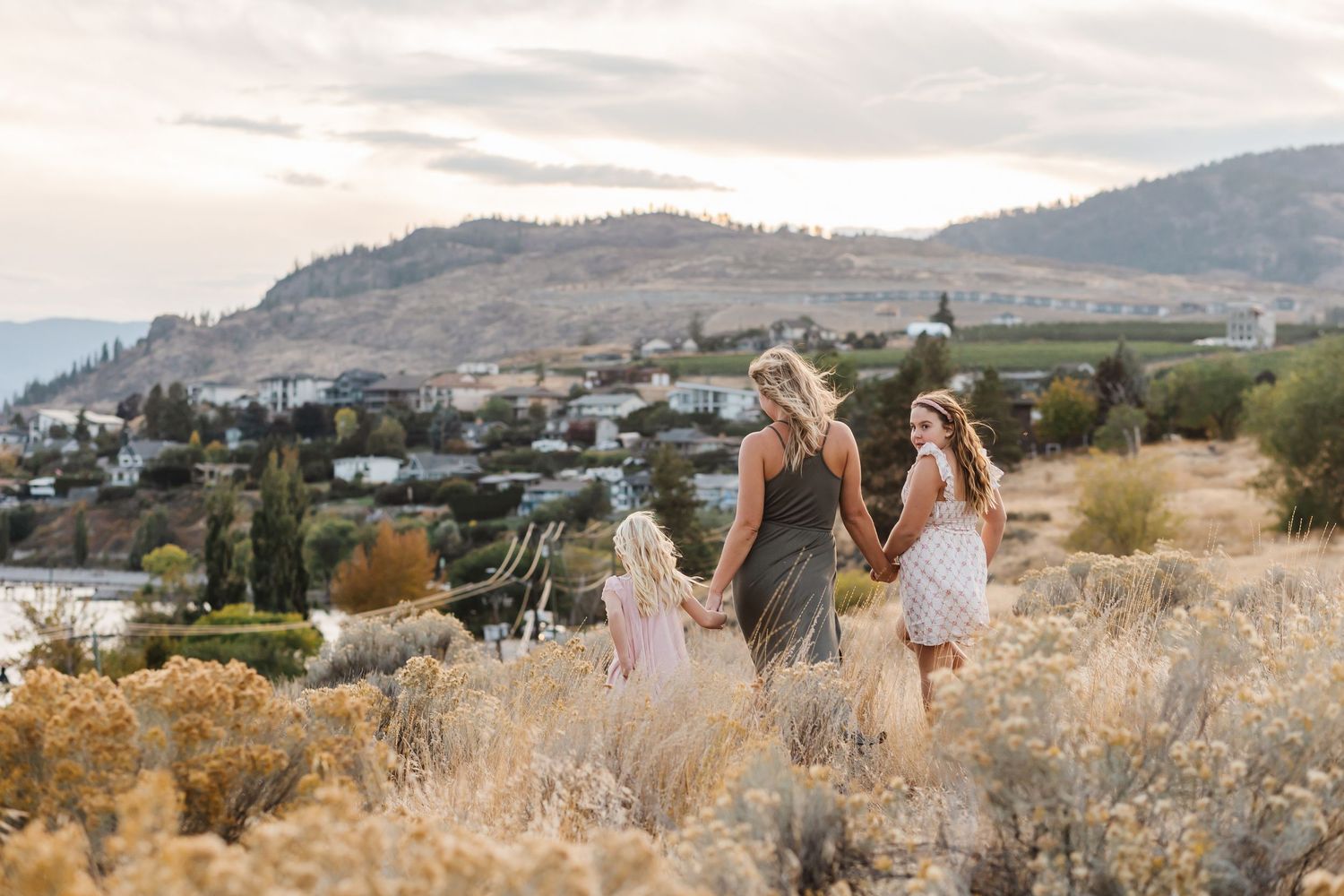 A group gathers in a scenic mountain meadow with golden grass at sunset for an outdoor celebration.