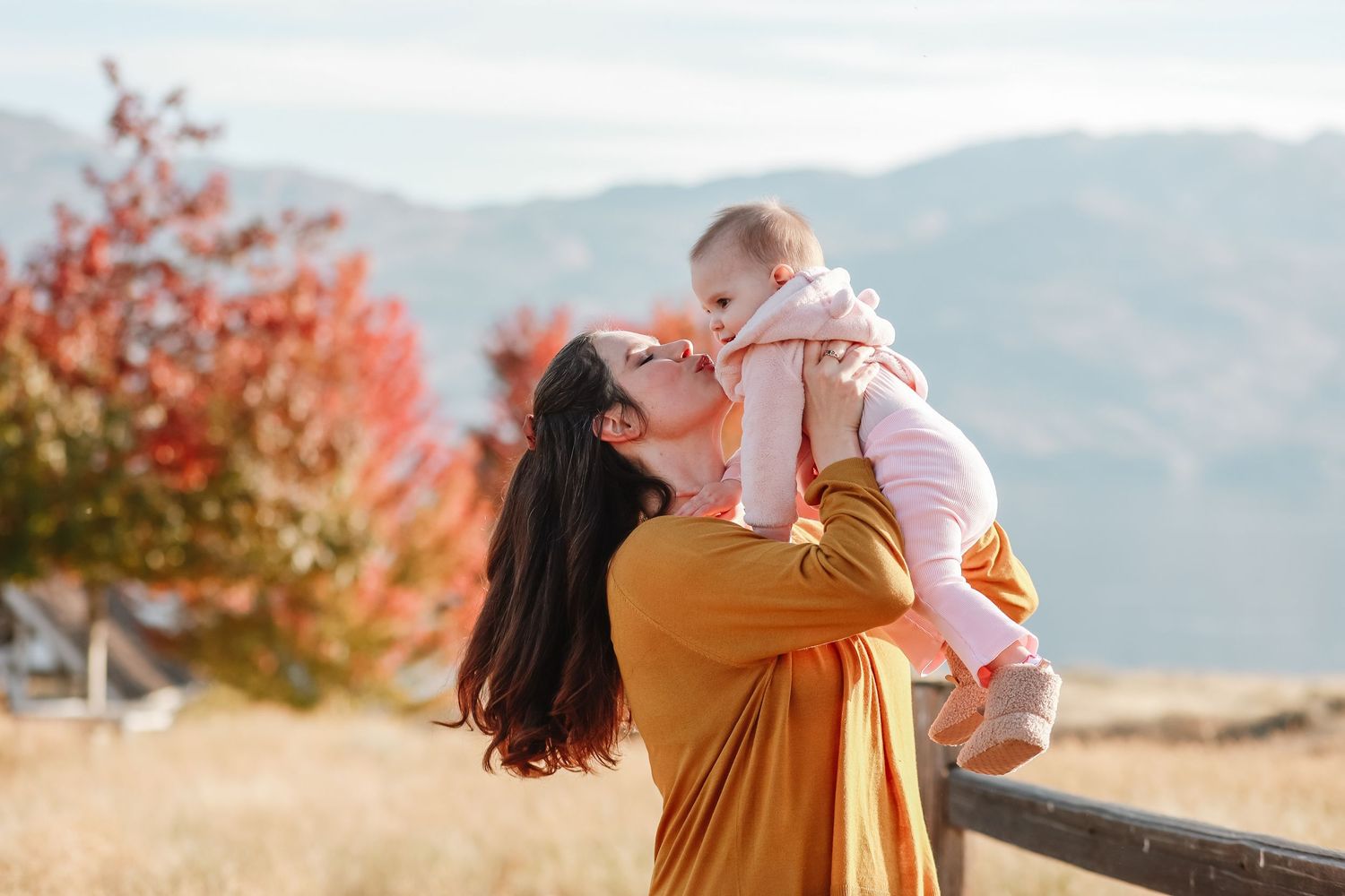 A candid photo captured outdoors with a mustard sweater and autumn foliage  in the mountain backdrop in West Kelowna at sanctuary gardens
