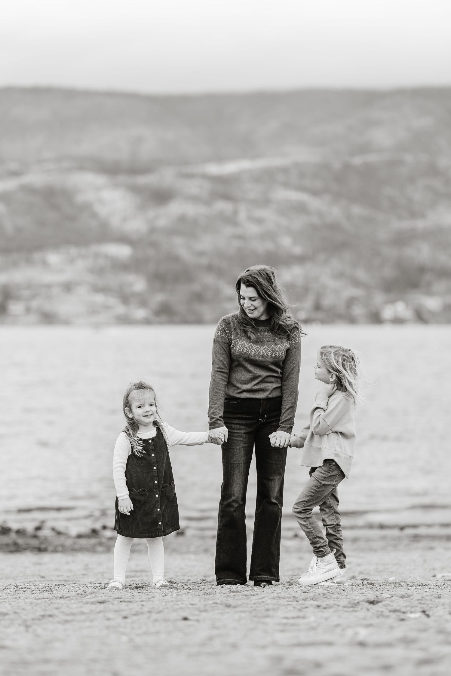 A black and white series of photos showing a family spending time together on a beach in casual attire.