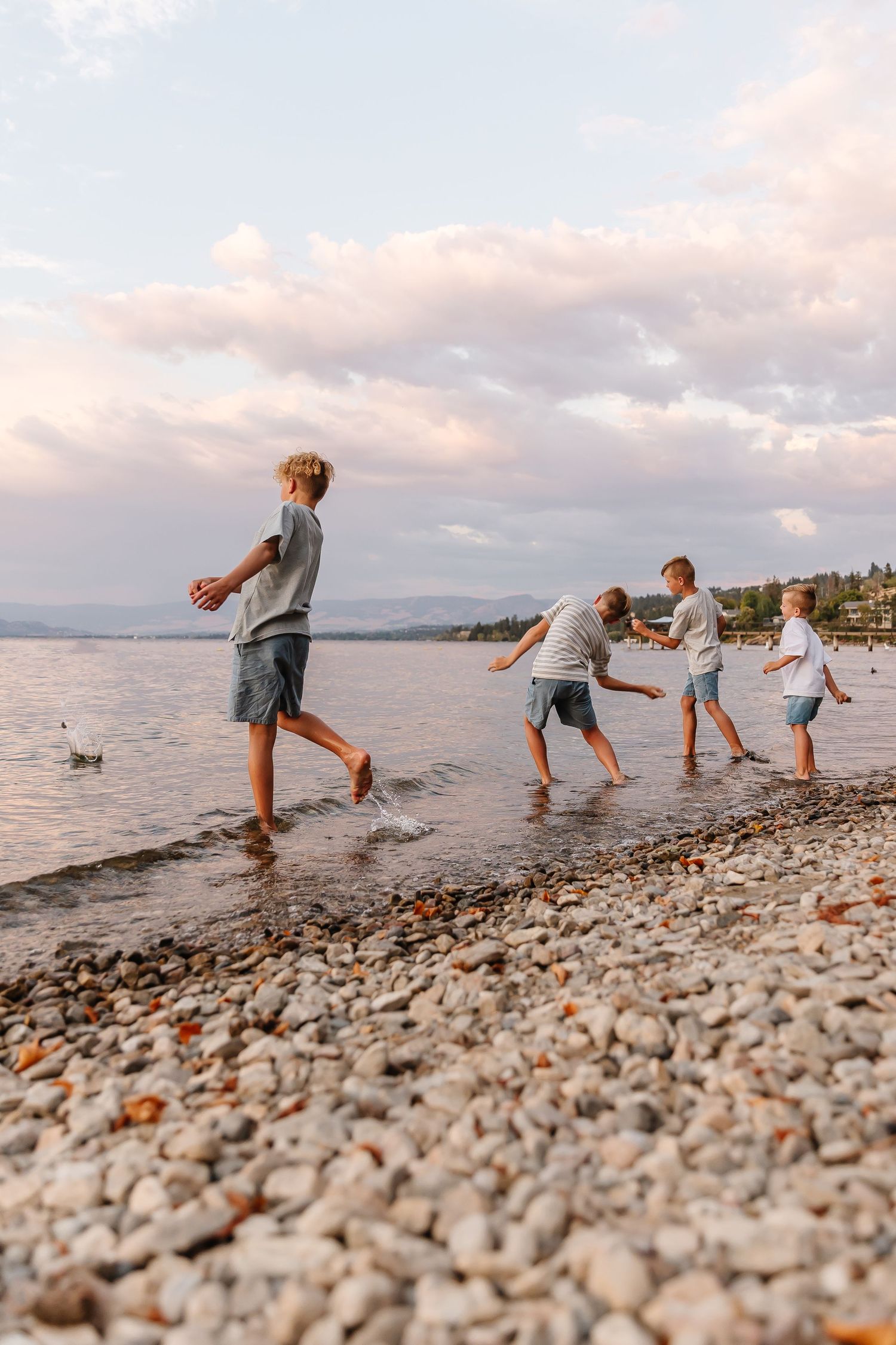 candid photoshoot of Sequence of playful stone skipping moments captured on a rocky beach at sunset in Kelowna at Bertram park creek