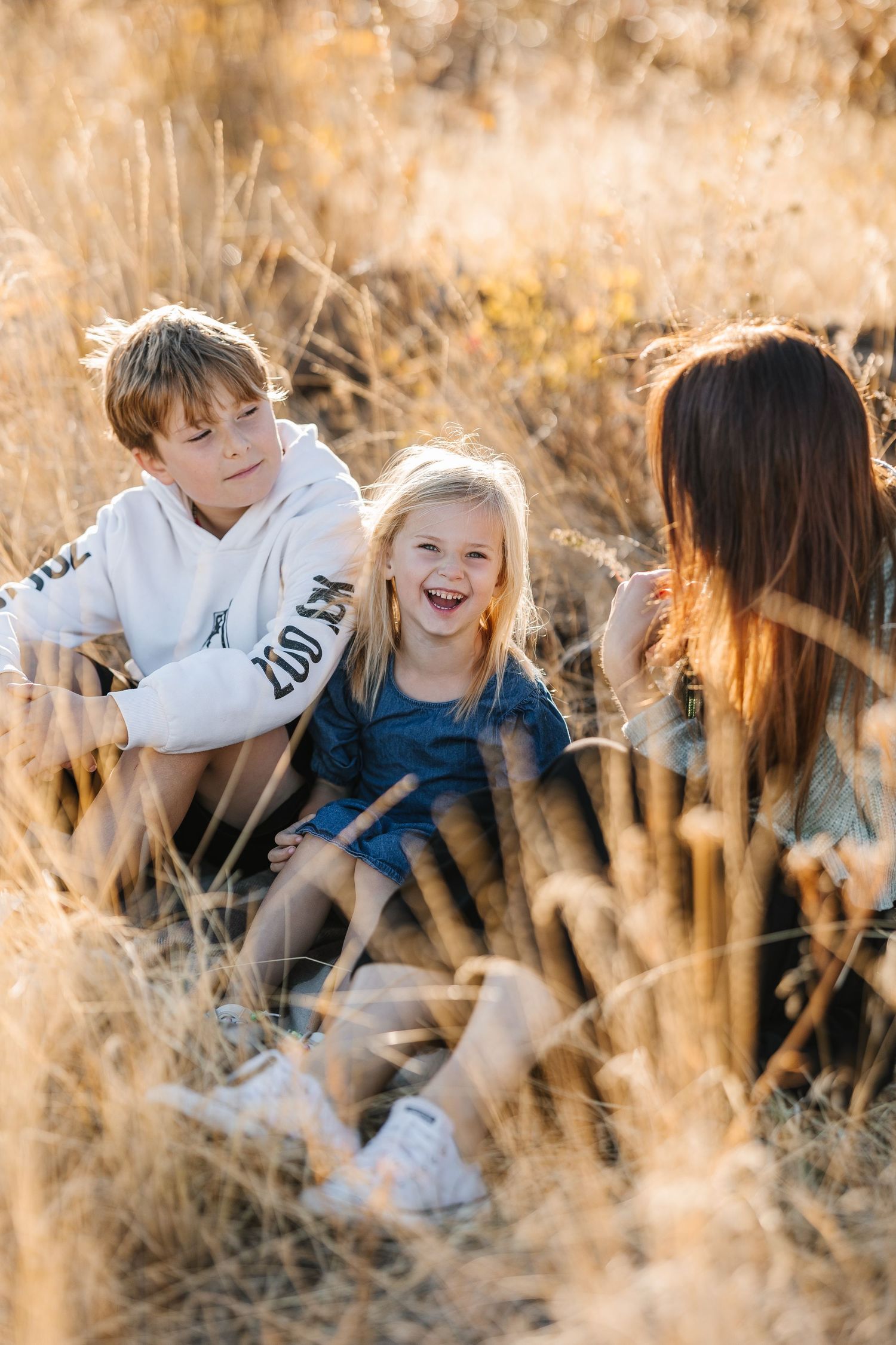 Candid moments of playful interaction in golden wheat field during sunset photo session.