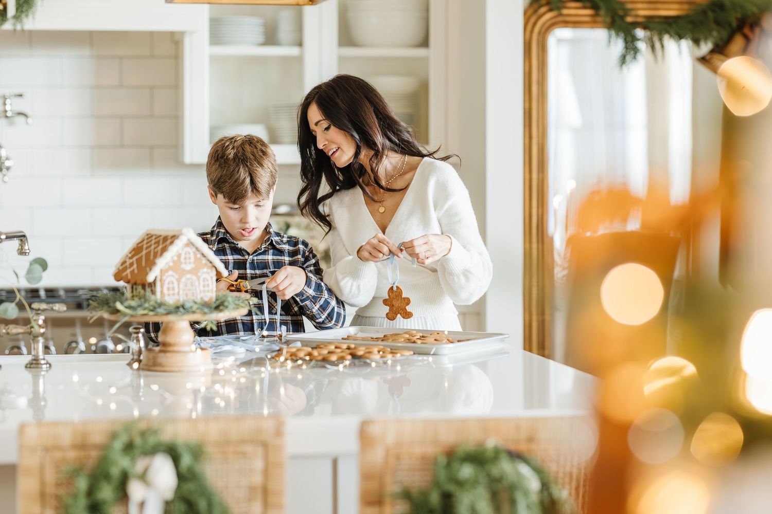 Family baking holiday cookies together in bright kitchen with Christmas decorations and warm lighting.