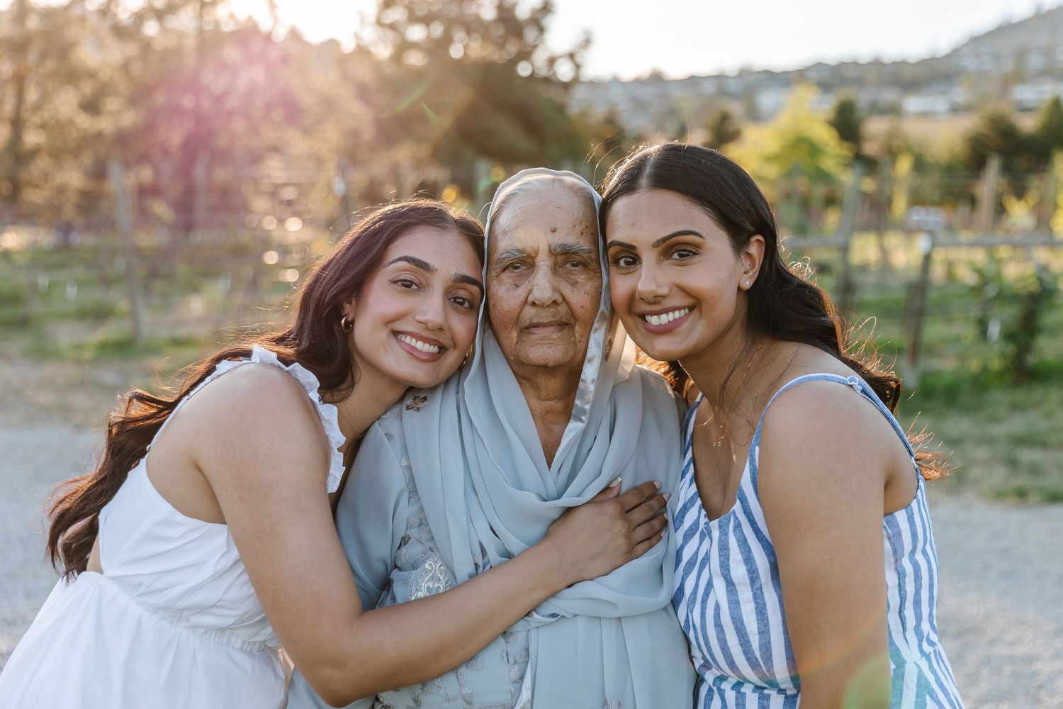 Family members embrace while posing together outdoors at sunset at quails gate in west Kelowna