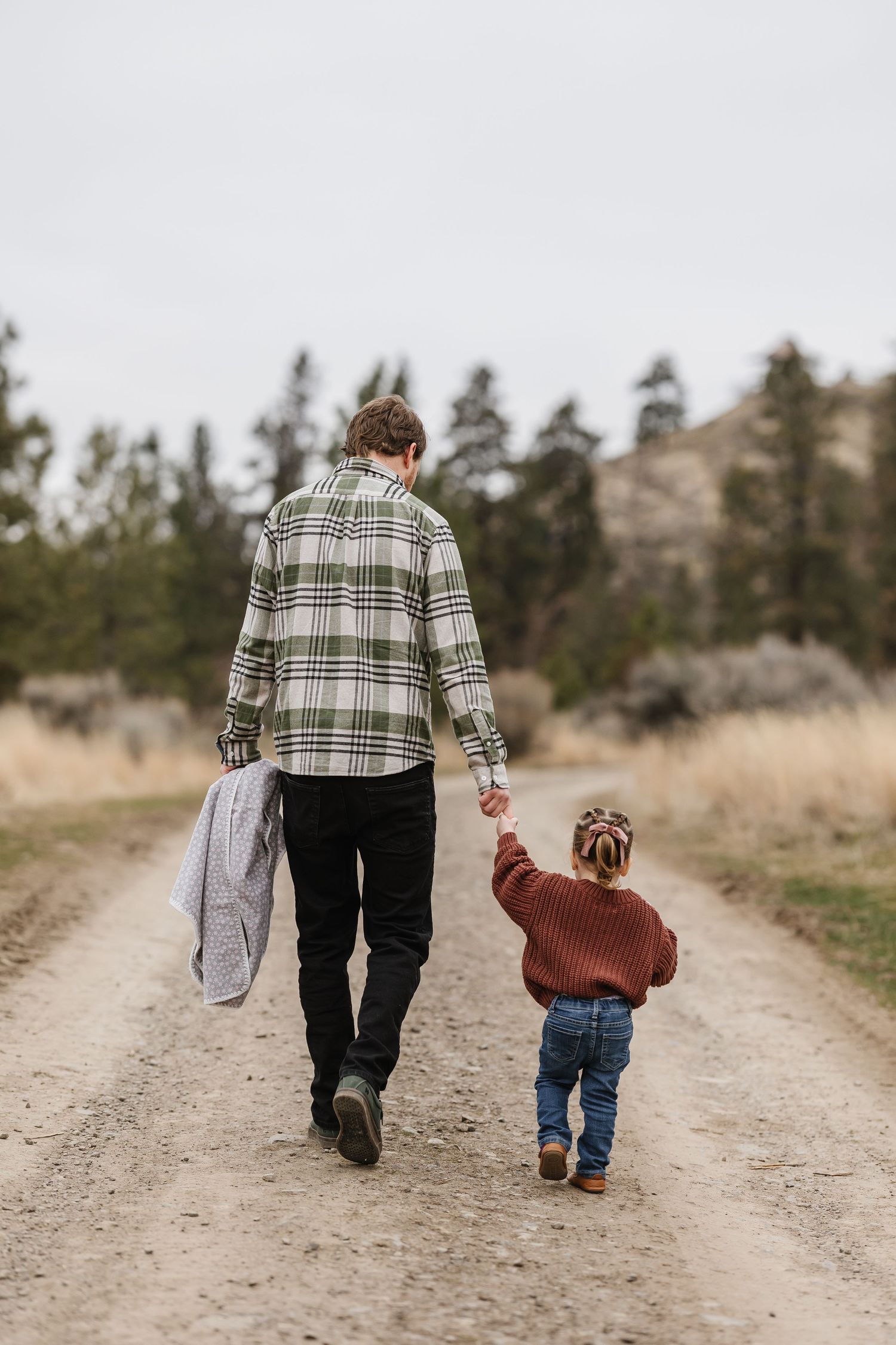 father and daughter casually walking down a trail at Knox mountain park in kelowna bc for family photos