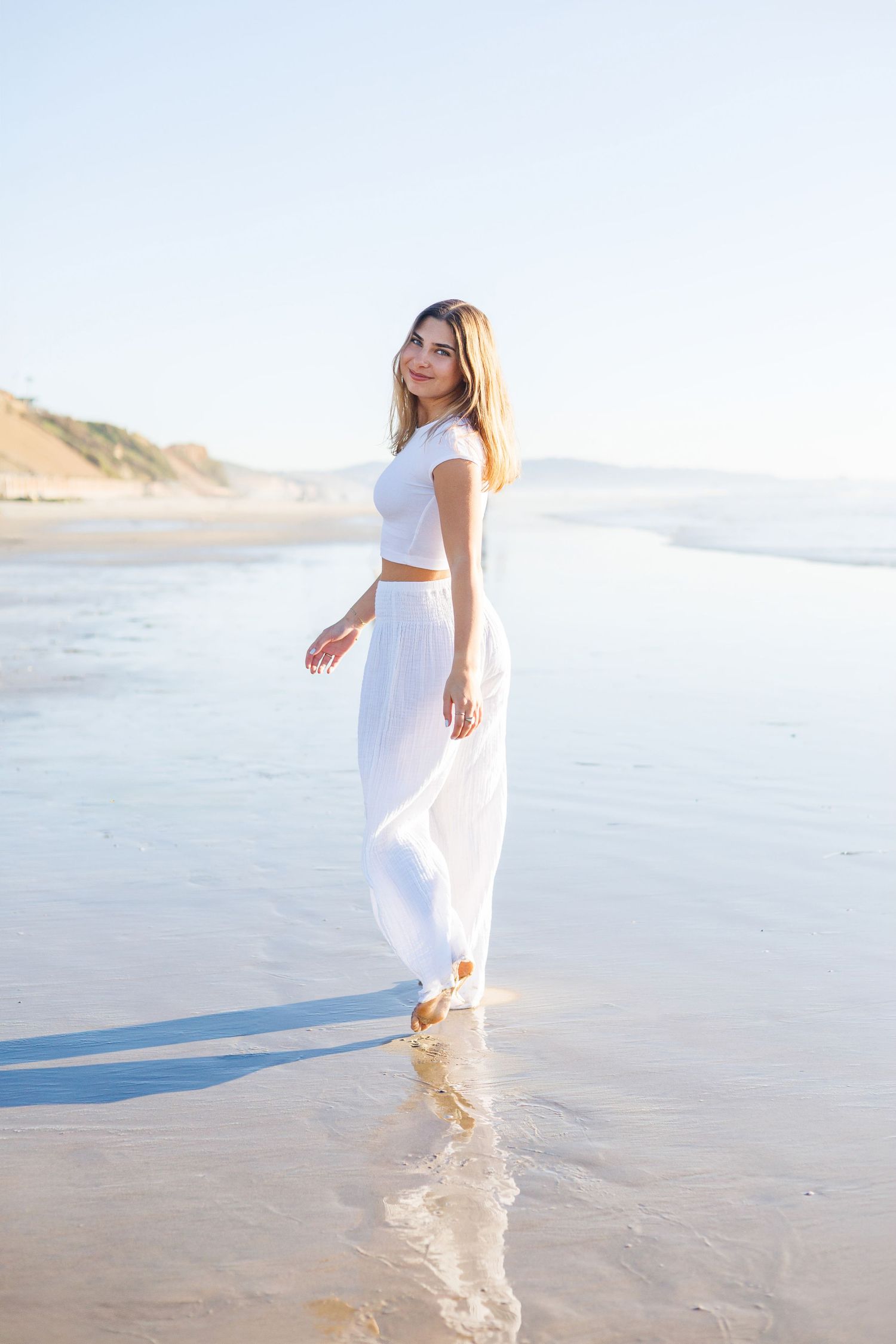 Woman in black off-shoulder dress twirling against white background.