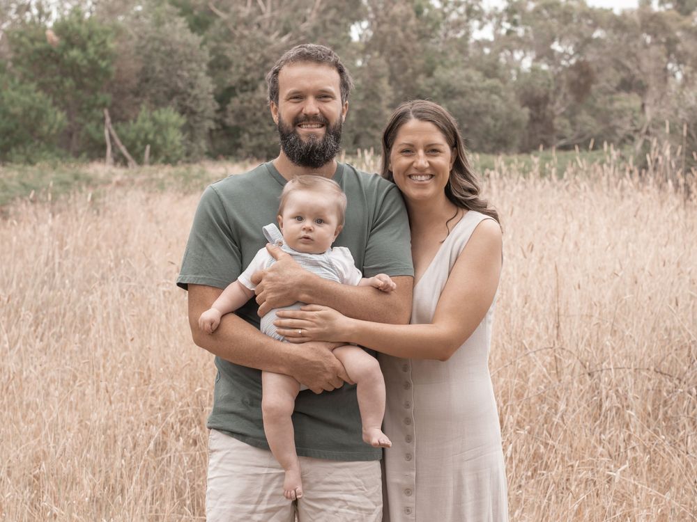 Family embraces in a sun-lit field of tall grass during golden hour outdoor photo session.