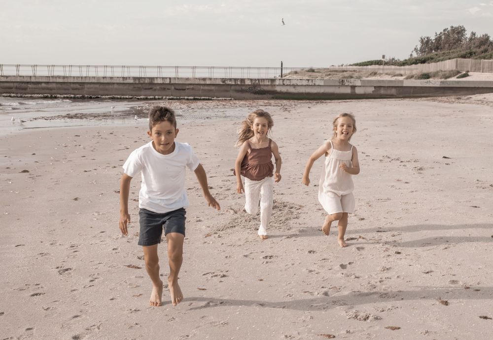 A sequence of photos showing people running and playing joyfully on a sandy beach at sunset.