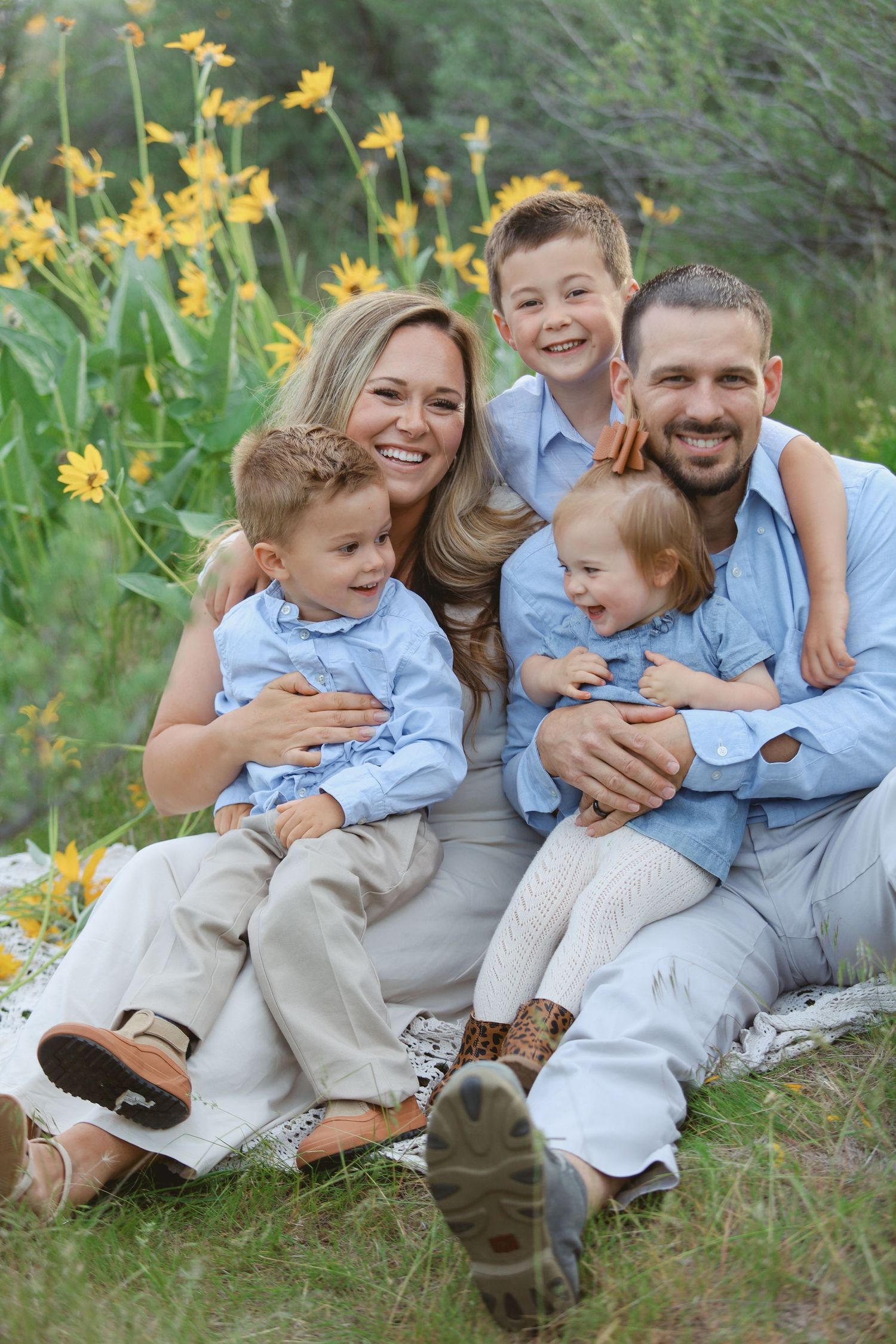 A joyful family photo session among yellow daffodils wearing coordinated blue and grey outfits.