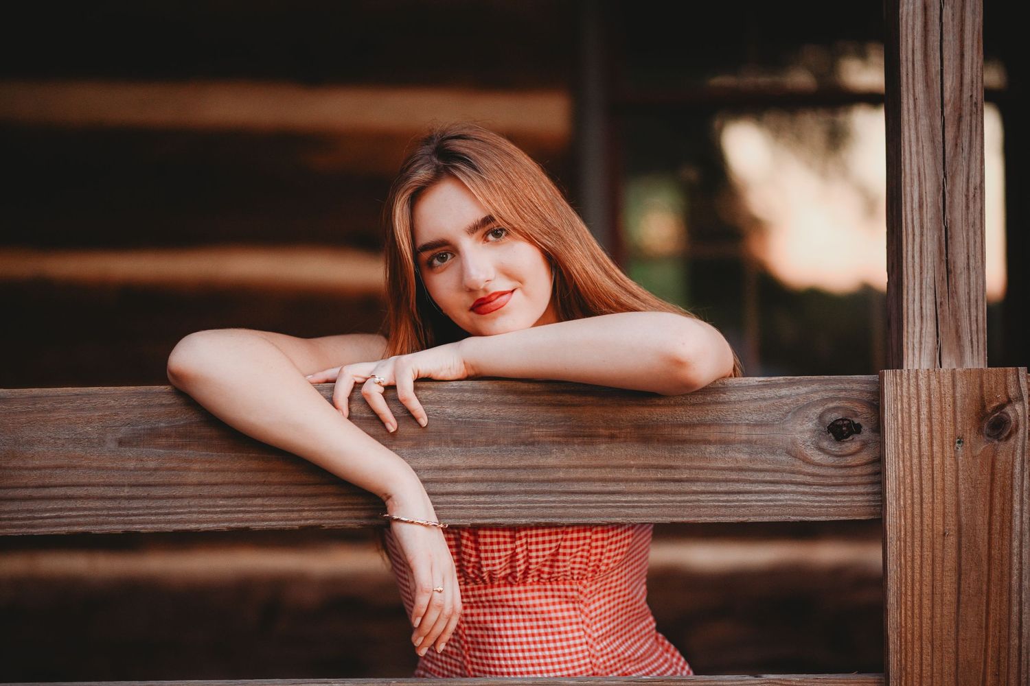 Artistic portrait through wooden fence slats creates moody rustic composition.