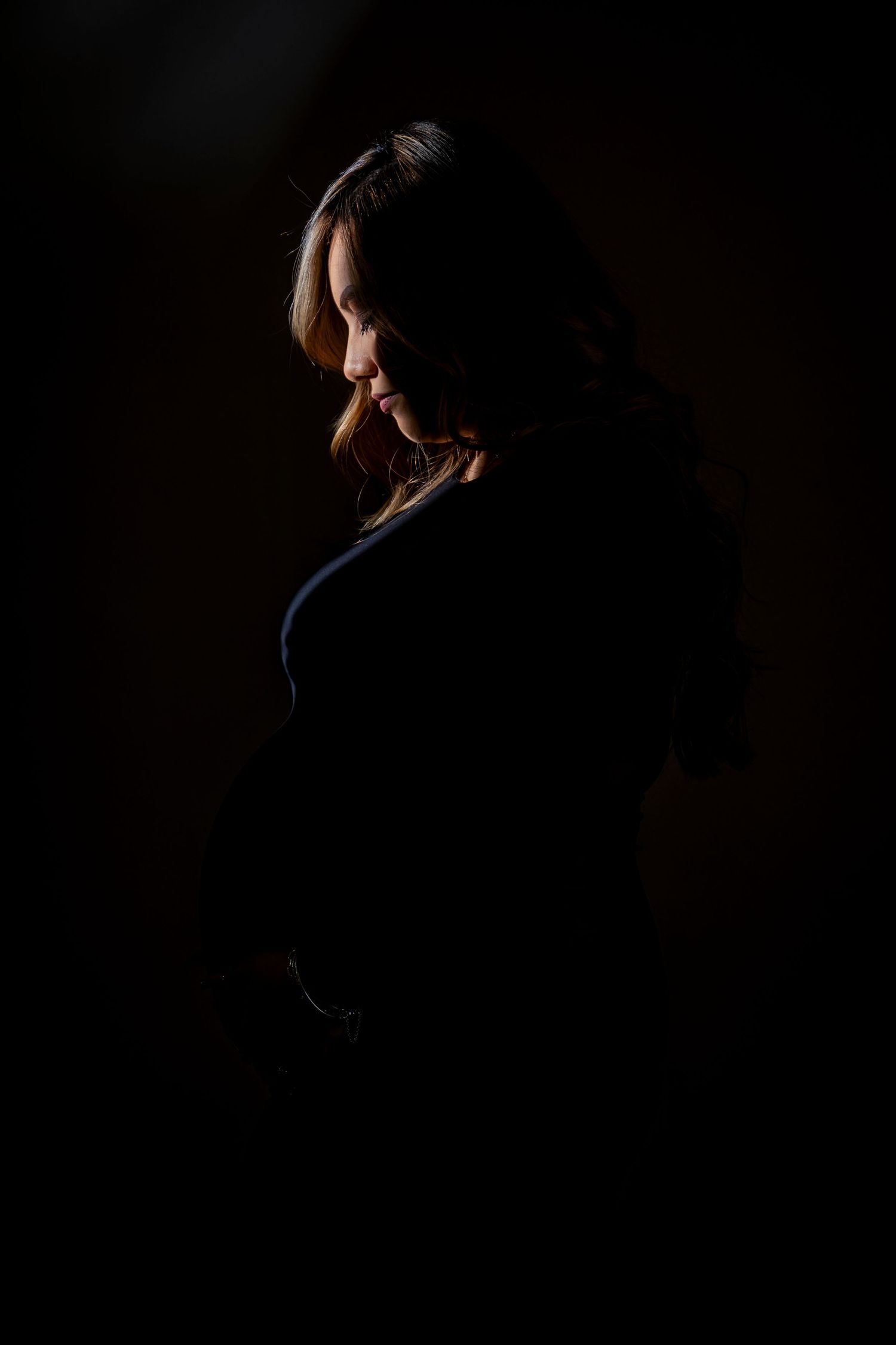 Dramatic side profile silhouette portrait against dark background with rim lighting.