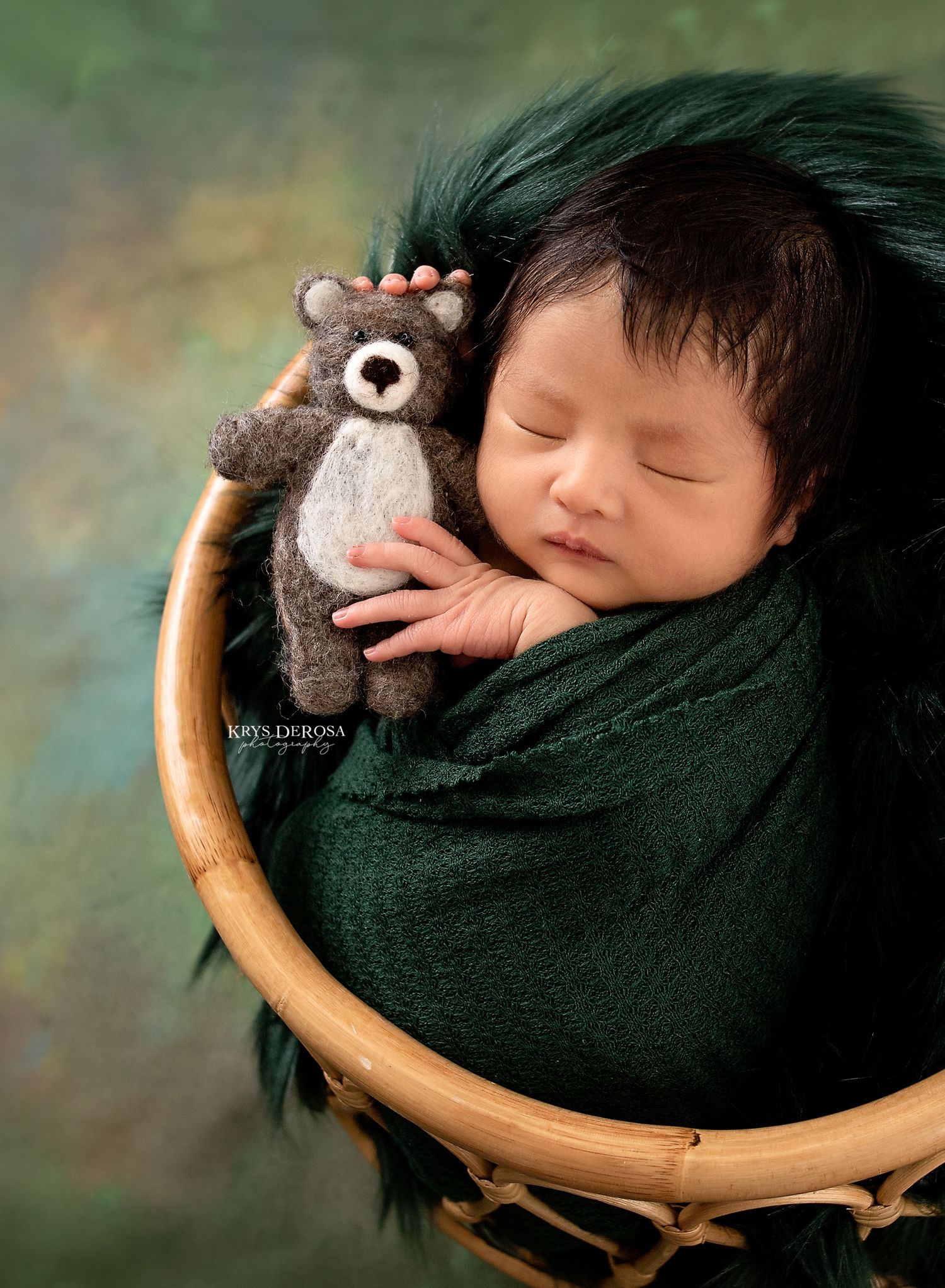 A sleeping newborn baby nestled in a bright blue fabric sling against a black background.