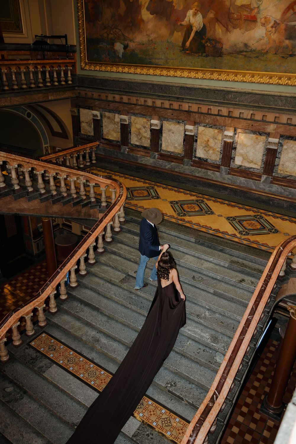A person lies on ornate wooden church pews inside a historic sanctuary with decorative murals and tiled floors.