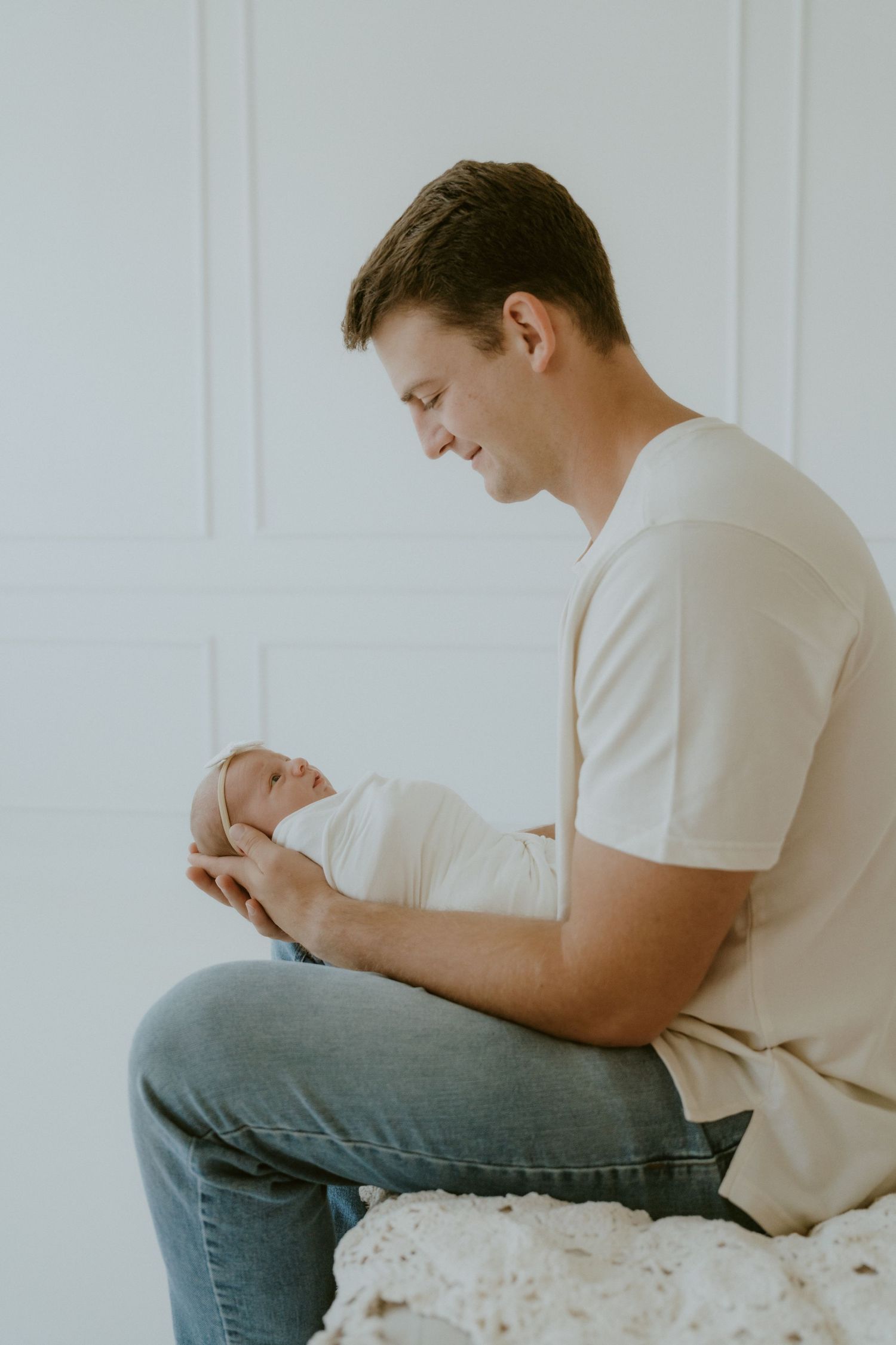 A tender moment between parent and infant in a bright minimalist setting.