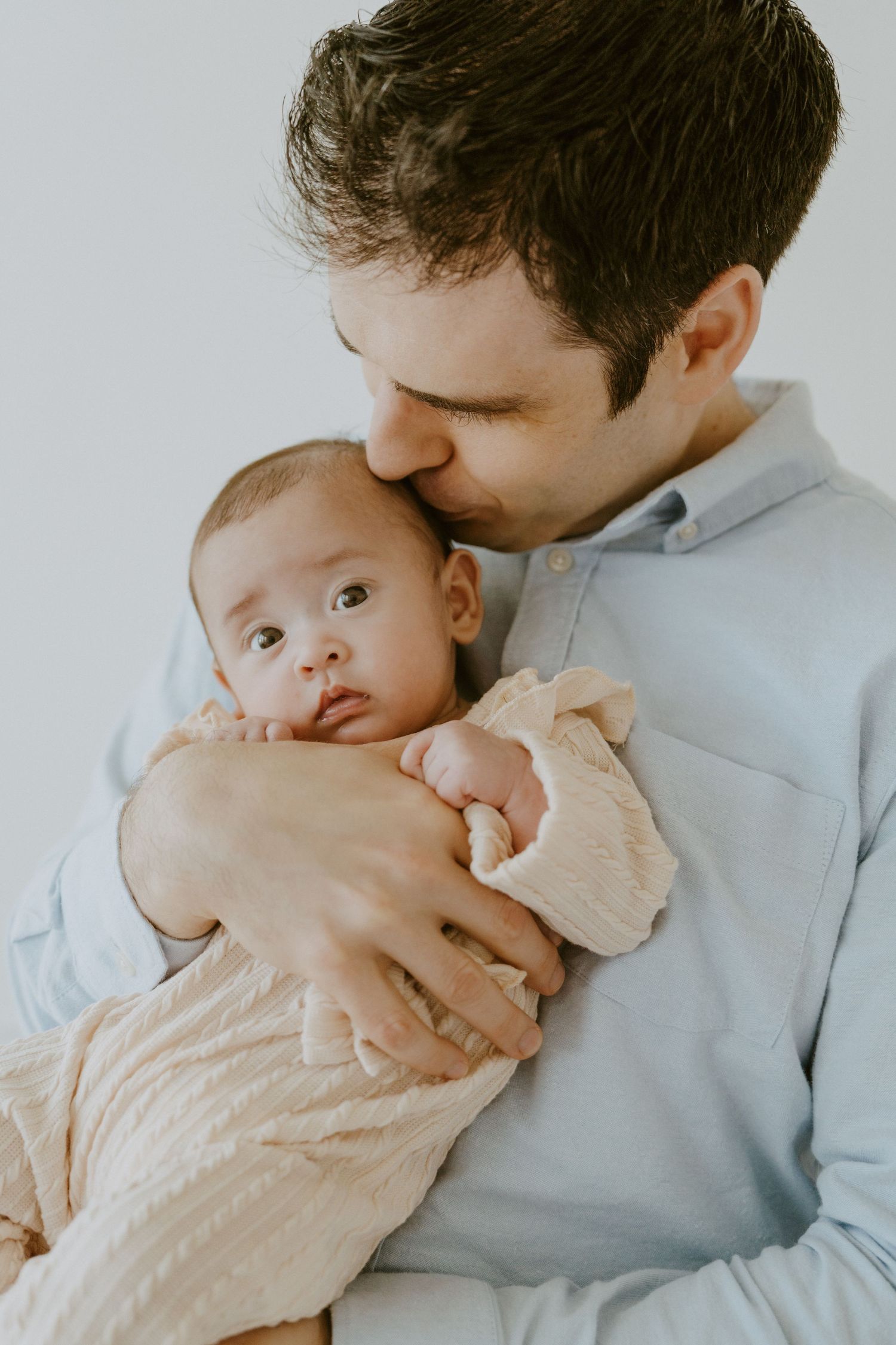 An intimate moment between parent and baby in soft neutral tones.