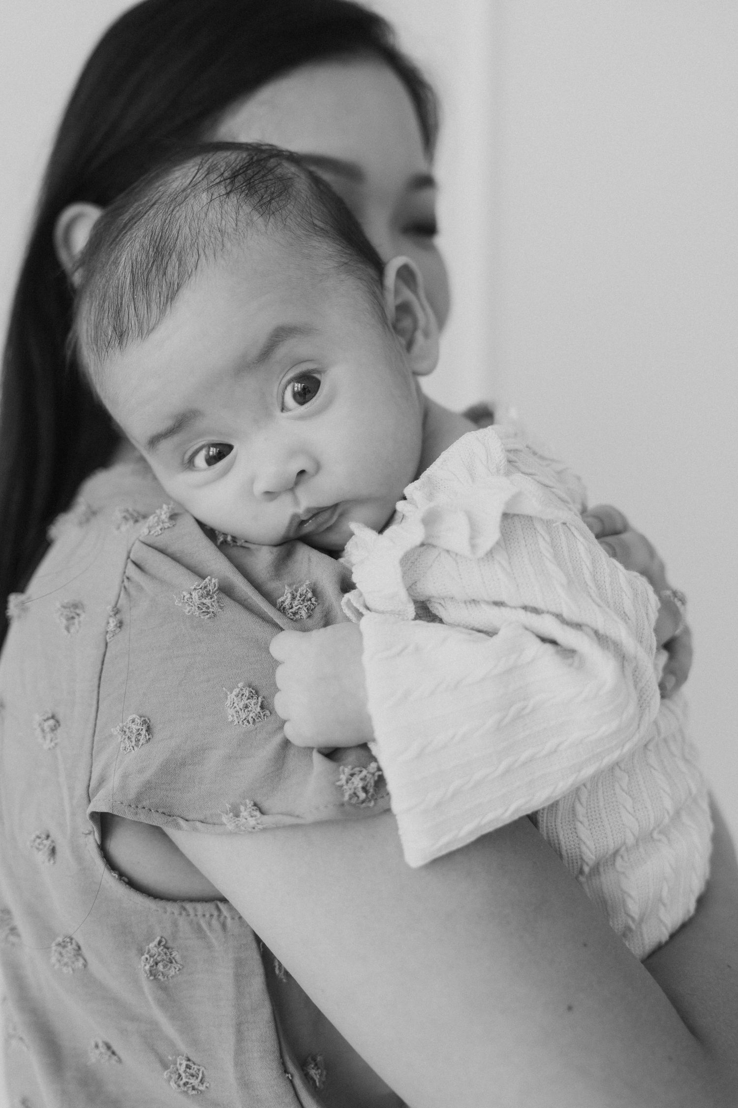 Black and white portrait of an infant being held in soft clothing.