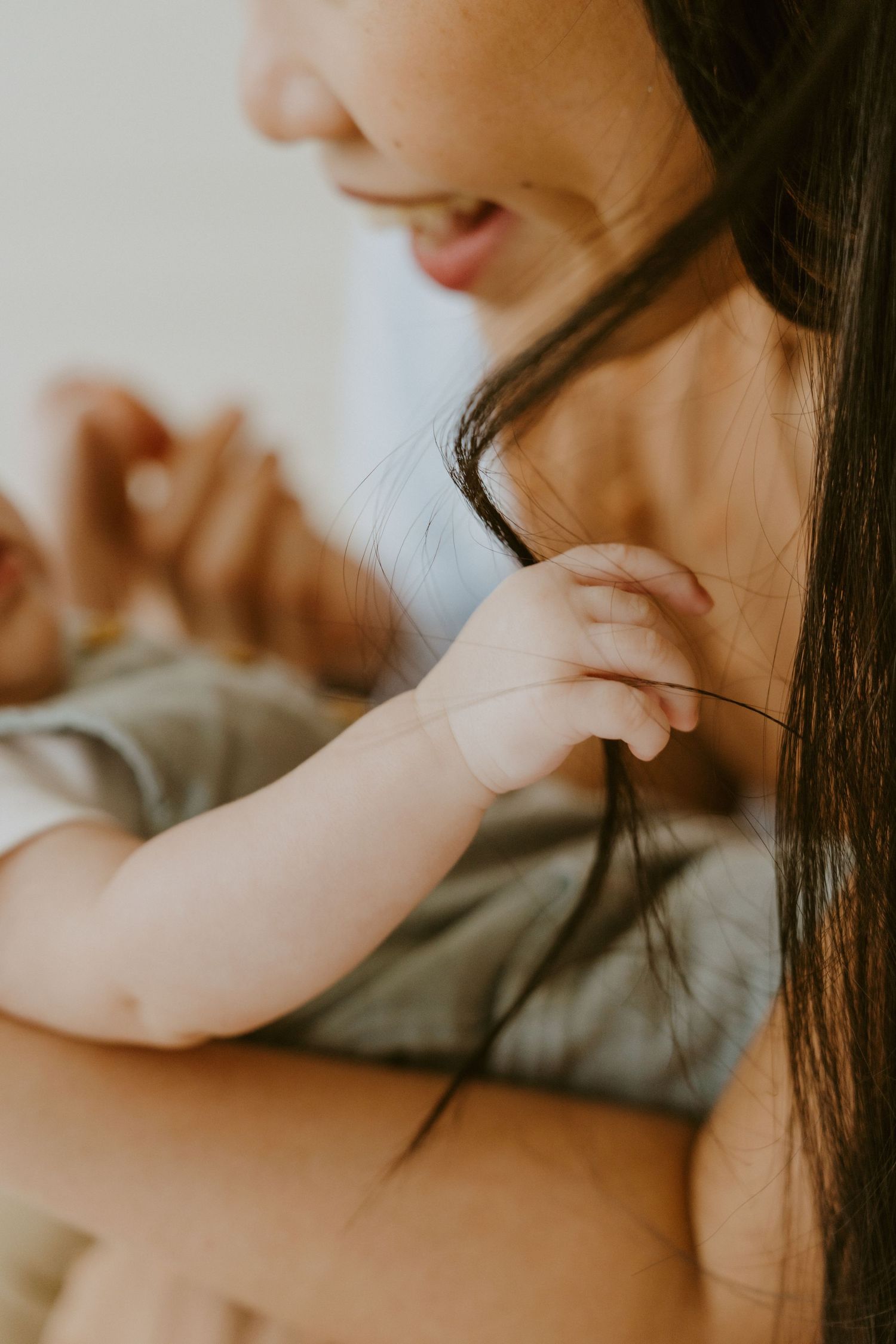 Close-up shot of a baby's hand gently touching long dark hair.