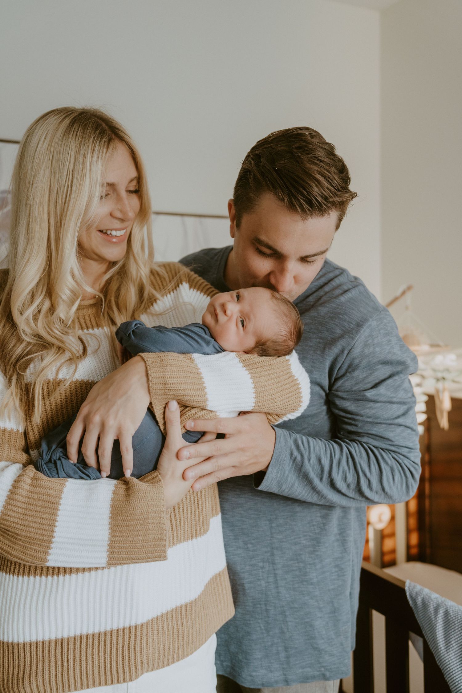 Loving parents sharing joyful moment with their newborn in cozy nursery setting.