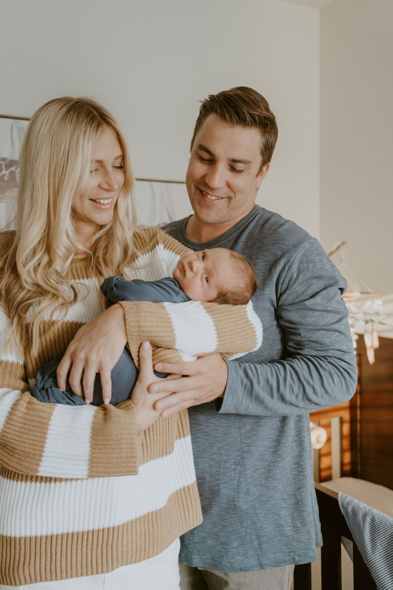 Happy couple gazing lovingly at their newborn baby in a bright nursery.