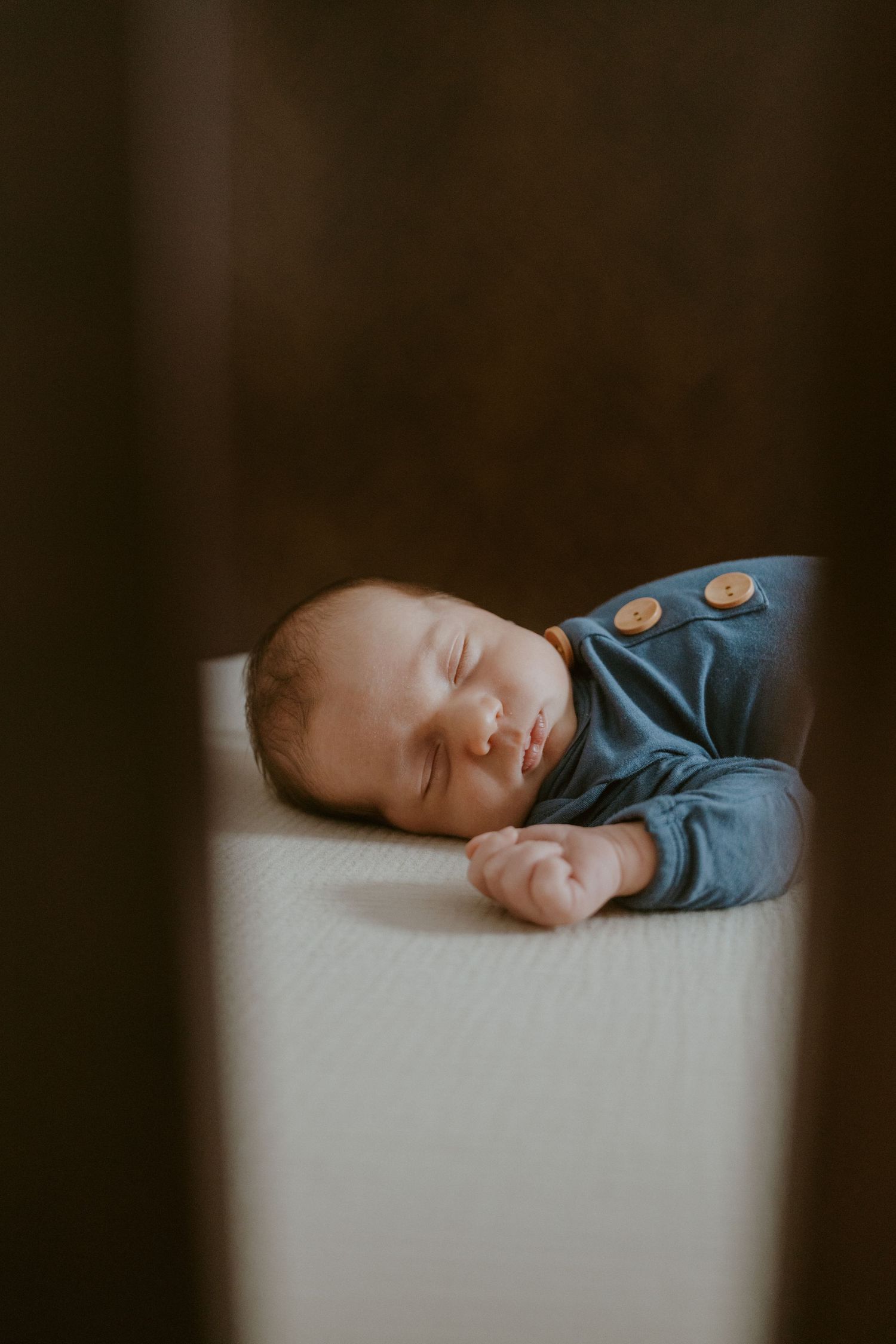 Peaceful sleeping newborn in blue outfit lying on white surface.