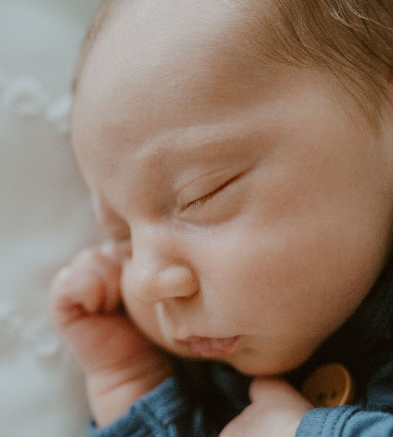Close-up of sleeping baby's face with peaceful expression against white bedding.