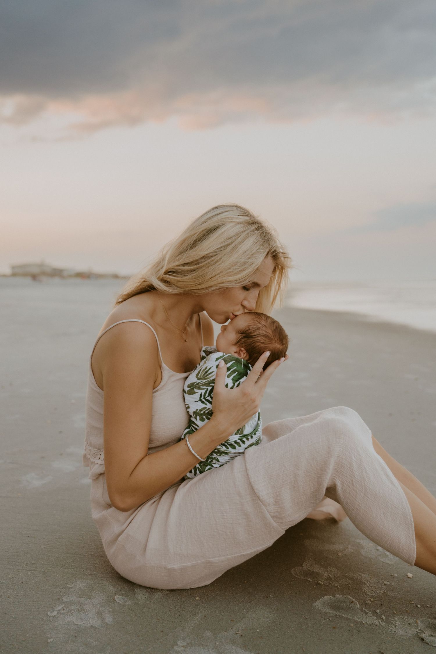 Tender moment at sunset on beach with baby in tropical print outfit.