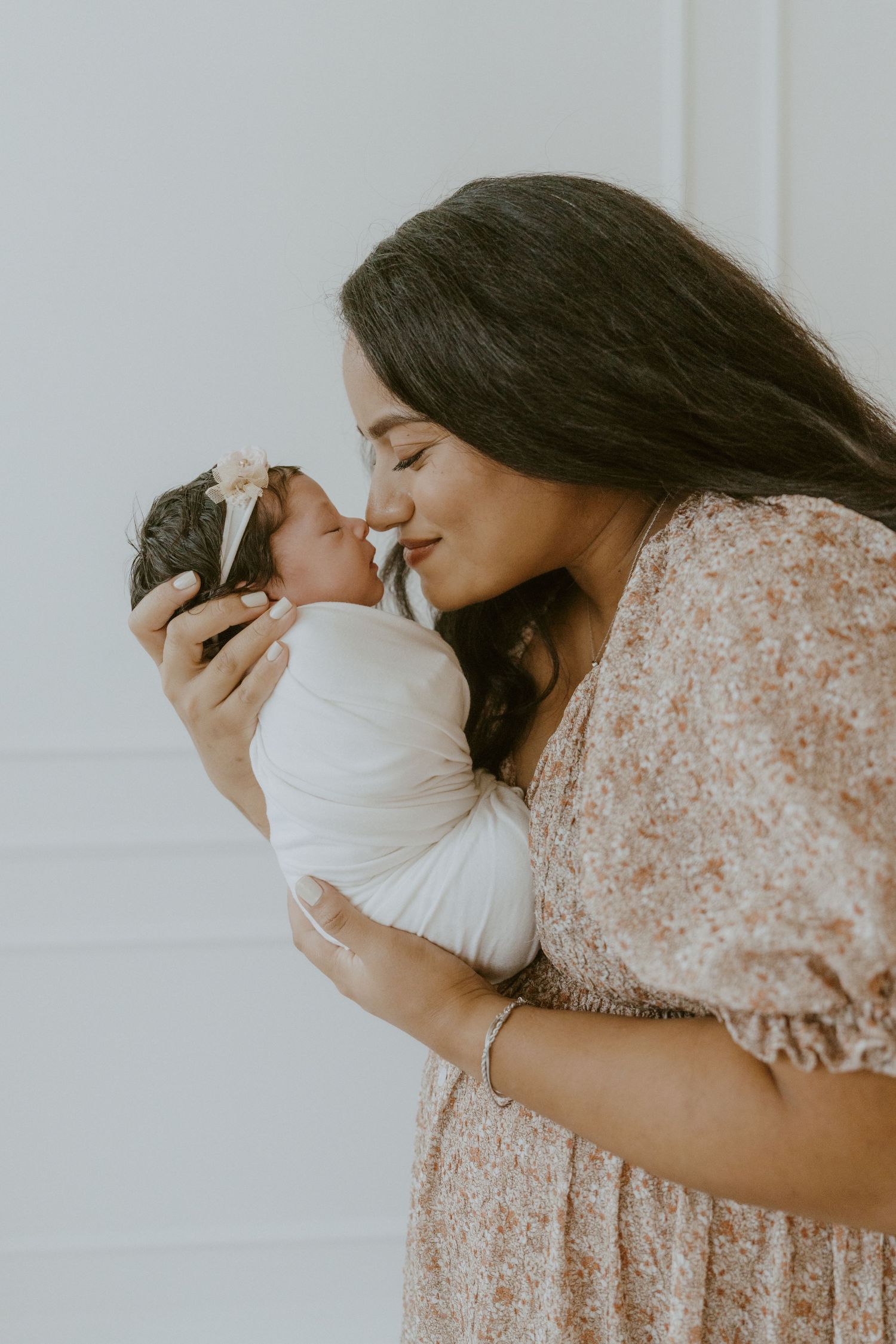 A tender moment captured between mother and newborn against a white background.