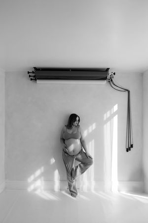 black and white image of woman standing against a wall with one leg up under photography backdrops during Billingham maternity session