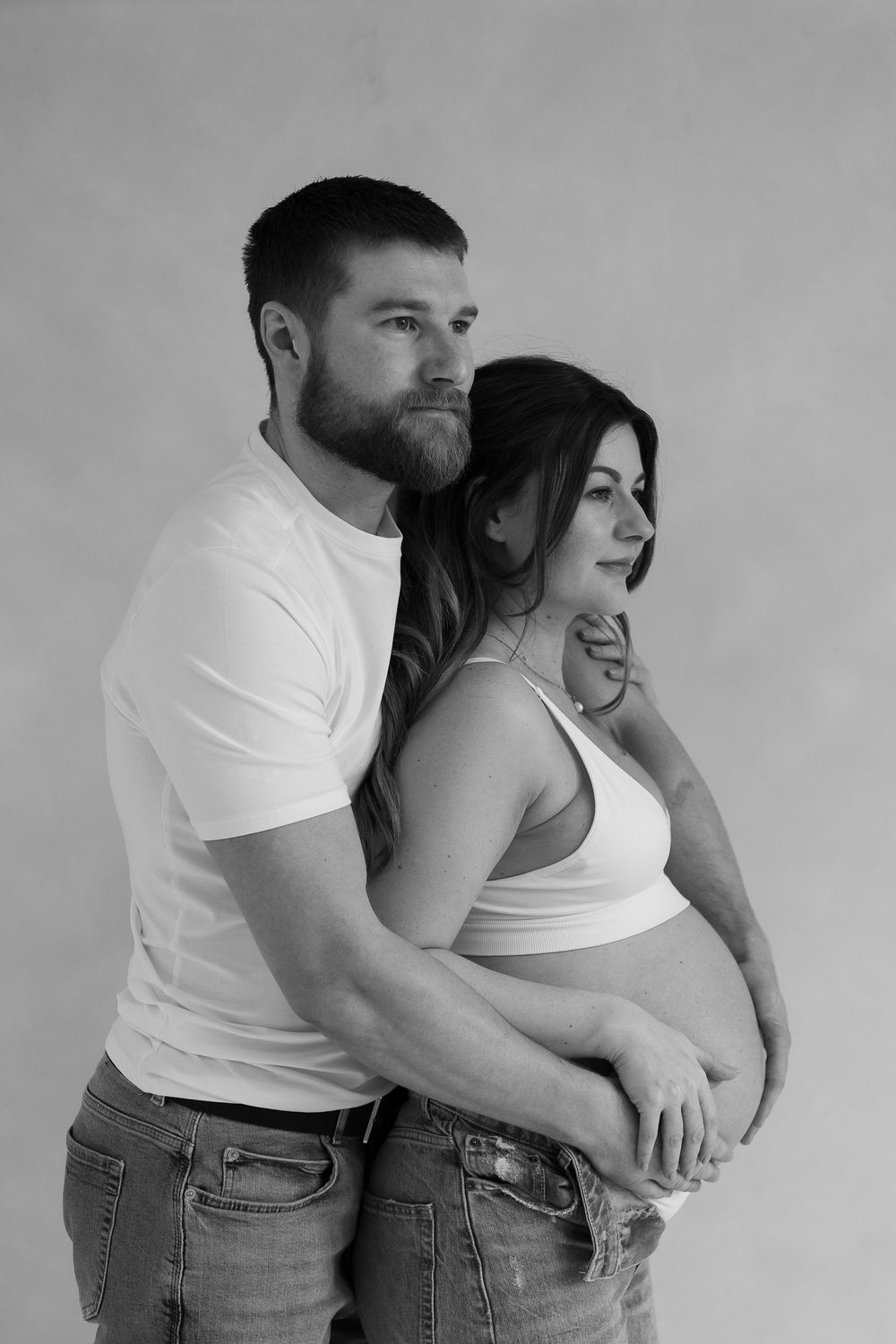 black and white image of couple close together as they embrace bump during their maternity session.