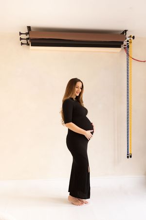 woman holding her bump in black dress under photography back drops during a maternity session based in Billingham